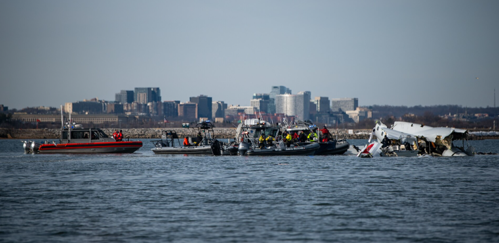 Washington, United States: Investigators probing the January 29 mid‑air collision between U.S. Army Black Hawk helicopter and American Airlines Flight 5342 over the Potomac River revealed a combination of faulty altitude data, communication failures, and ignored safety warnings as contributing factors to the disaster that killed all 67 people aboard the commercial aircraft.
During three days of public hearings held this week, the National Transportation Safety Board (NTSB) disclosed evidence that the Black Hawk was operating as much as 100 feet higher than its altimeter indicated, breaching the restricted ceiling for helicopters transiting the congested Reagan National Airport corridor. Officials said the helicopter’s barometric altitude sensors were incorrectly calibrated, a condition also found in similar Army aircraft.
“Altitude deviations of that magnitude are unacceptable in such tightly controlled airspace,” said NTSB Chair Jennifer Homendy, noting that the military’s existing tolerance for up to 100 feet of variance was now under review.
The hearing also detailed a communication breakdown moments before the collision. A radio transmission from the Black Hawk reportedly “stepped on” the tower controller’s instructions, obscuring critical clearance information. Compounding the error, a single controller was managing both local helicopter and fixed‑wing operations, an arrangement the NTSB described as “operationally unsound for high‑density traffic periods.”
 The Federal Aviation Administration faced sharp criticism for not acting on repeated warnings from controllers and internal safety analysts. Between 2021 and 2024, more than 15,000 near‑miss events were recorded nationwide, including 84 in the Washington National airspace region. Despite internal proposals to chart helicopter “hot spots” and segregate their routes, no permanent changes were implemented prior to the crash.
According to Reuters, Transportation Secretary Sean Duffy told lawmakers that, “This accident reflects systemic failures that cannot be excused by procedural norms or military exemptions.”
 On Tuesday, Senator Ted Cruz introduced bipartisan legislation requiring all military and training helicopters operating near commercial corridors to activate ADS‑B Out tracking, which broadcasts precise position and altitude to air traffic control and other aircraft. The bill also calls for a comprehensive review of flight routing in mixed‑use airspace and a federal audit of aviation oversight practices.
The Army confirmed that ADS‑B tracking had been disabled during the helicopter’s test mission, a common practice for certain military flights but one that reduced situational awareness in an already crowded corridor.
Families of victims, along with aviation safety advocates, have welcomed the proposed reforms, though the NTSB cautioned that a final report is not expected until 2026.

