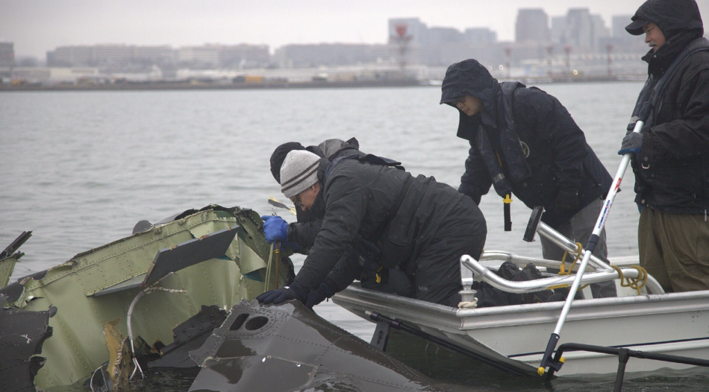 SOCIAL: The NTSB’s investigation into the January 29 Potomac River mid‑air collision between U.S. Army Black Hawk helicopter and American Airlines Flight 5342, which killed 67 people, has revealed a combination of technical errors and systemic oversight failures. Data showed the helicopter was flying 80–100 feet higher than indicated due to faulty altimeter calibration, breaching its permitted altitude in congested airspace. Communication breakdowns further contributed, as radio transmissions from the helicopter cut off key air traffic control instructions, while a single controller handled both helicopter and fixed‑wing operations.
The FAA faced heavy criticism for ignoring repeated safety warnings and failing to implement proposals to map helicopter “hot spots” or segregate routes, despite more than 15,000 near‑misses nationwide and 84 in the Washington region between 2021 and 2024. Transportation Secretary Sean Duffy called the crash a result of “systemic failures,” and NTSB Chair Jennifer Homendy emphasized the preventable nature of the tragedy. In response, bipartisan legislation has been introduced requiring ADS‑B tracking for military and training helicopters and a federal audit of airspace oversight. The NTSB’s final report is expected in 2026.
Washington, United States: Investigators probing the January 29 mid‑air collision between U.S. Army Black Hawk helicopter and American Airlines Flight 5342 over the Potomac River revealed a combination of faulty altitude data, communication failures, and ignored safety warnings as contributing factors to the disaster that killed all 67 people aboard the commercial aircraft.
During three days of public hearings held this week, the National Transportation Safety Board (NTSB) disclosed evidence that the Black Hawk was operating as much as 100 feet higher than its altimeter indicated, breaching the restricted ceiling for helicopters transiting the congested Reagan National Airport corridor. Officials said the helicopter’s barometric altitude sensors were incorrectly calibrated, a condition also found in similar Army aircraft.
“Altitude deviations of that magnitude are unacceptable in such tightly controlled airspace,” said NTSB Chair Jennifer Homendy, noting that the military’s existing tolerance for up to 100 feet of variance was now under review.
The hearing also detailed a communication breakdown moments before the collision. A radio transmission from the Black Hawk reportedly “stepped on” the tower controller’s instructions, obscuring critical clearance information. Compounding the error, a single controller was managing both local helicopter and fixed‑wing operations, an arrangement the NTSB described as “operationally unsound for high‑density traffic periods.”
 The Federal Aviation Administration faced sharp criticism for not acting on repeated warnings from controllers and internal safety analysts. Between 2021 and 2024, more than 15,000 near‑miss events were recorded nationwide, including 84 in the Washington National airspace region. Despite internal proposals to chart helicopter “hot spots” and segregate their routes, no permanent changes were implemented prior to the crash.
According to Reuters, Transportation Secretary Sean Duffy told lawmakers that, “This accident reflects systemic failures that cannot be excused by procedural norms or military exemptions.”
 On Tuesday, Senator Ted Cruz introduced bipartisan legislation requiring all military and training helicopters operating near commercial corridors to activate ADS‑B Out tracking, which broadcasts precise position and altitude to air traffic control and other aircraft. The bill also calls for a comprehensive review of flight routing in mixed‑use airspace and a federal audit of aviation oversight practices.
The Army confirmed that ADS‑B tracking had been disabled during the helicopter’s test mission, a common practice for certain military flights but one that reduced situational awareness in an already crowded corridor.
Families of victims, along with aviation safety advocates, have welcomed the proposed reforms, though the NTSB cautioned that a final report is not expected until 2026.
