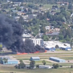 Montana, United States: A small private aircraft crash-landed into multiple parked planes at Kalispell City Airport on Monday afternoon, sparking an intense fire but resulting in no serious injuries, authorities confirmed. The incident involved a 2011-built Socata TBM 700 turboprop, registered to Meter Sky LLC of Pullman, Washington. According to the Kalispell Fire Department, the single-engine plane was carrying four people, the pilot and three passengers when it attempted to land at around 2:00 p.m. local time. Initial reports from Kalispell Fire Chief Dan Pearson indicate that the TBM 700 touched down normally but lost directional control during rollout. The aircraft veered off the runway and collided with several parked planes on the apron. The collision ruptured fuel lines, triggering a blaze that quickly spread to the nearby grassy area adjacent to the tarmac. All four occupants managed to evacuate the aircraft before flames engulfed it. Two people suffered minor injuries and received treatment on-site, while the other two were unhurt. No injuries were reported among ground personnel. Multiple firefighting units from Kalispell and surrounding districts responded within minutes. Eyewitnesses described the crash as sudden and violent. Mark Grant, manager of the Aero Inn located near the airport, recounted to AP NEWS the moment of impact: “It was like sticking your head inside a bass drum and someone hitting it with all their might. The sound rattled the windows.” Several onlookers captured videos that circulated widely on social media, showing thick columns of black smoke rising from the airfield as emergency crews rushed to the scene. The Federal Aviation Administration (FAA) confirmed it has opened a preliminary inquiry into the crash, while the National Transportation Safety Board (NTSB) will lead the formal investigation. The investigators will examine factors including runway surface conditions, aircraft mechanical integrity, and potential pilot error. The TBM 700’s flight data and cockpit voice recorders, though not required for all private planes, will be checked if installed. The NTSB’s initial report is expected within two weeks, but a final determination could take up to a year.