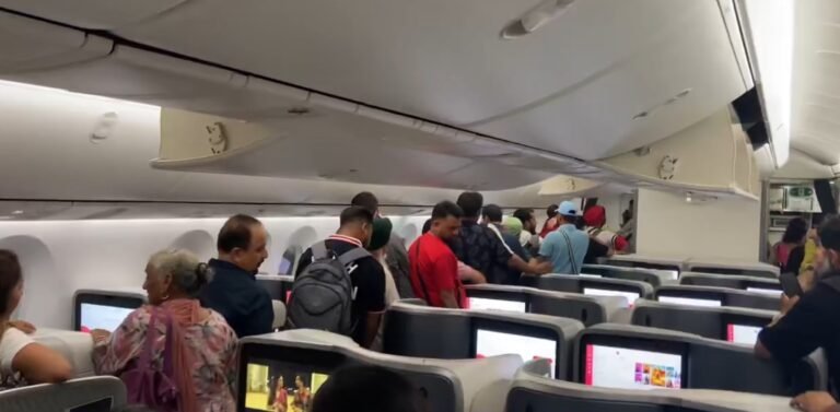 New Delhi, India: Over 200 passengers on board Air India’s Singapore-bound flight from Delhi faced a gruelling night after a cabin cooling failure delayed their departure by nearly six hours, forcing them to deplane and wait in the terminal before a replacement aircraft was arranged. The incident occurred on Flight AI2380, operated with a Boeing 787-9 Dreamliner, which was scheduled to depart Indira Gandhi International Airport at around 11:00 PM on Wednesday night. Shortly after boarding, the aircraft reportedly experienced faults with its air conditioning system and electrical power supply, resulting in rising cabin temperatures. According to passengers, the situation quickly became uncomfortable as the cabin’s temperature climbed. Several travellers shared videos on social media showing people fanning themselves with newspapers and magazines. Some posts described young children and elderly passengers struggling with the heat during the extended wait. Passengers remained inside the aircraft for close to two hours before crew instructed them to disembark and return to the terminal. The decision was taken after engineers determined the issue could not be resolved on the spot. In a statement, Air India acknowledged the disruption, citing a “cabin cooling issue on ground prior to departure” as the cause. The airline said that its ground teams provided regular updates, refreshments, and meals while travellers waited in the terminal. “We sincerely regret the inconvenience caused to our passengers. The safety and well-being of everyone on board remain our top priority,” the airline said. With the Dreamliner grounded for repairs, Air India deployed a replacement aircraft. The rescheduled flight finally took off at 5:36 AM IST on Thursday, nearly six hours behind schedule.