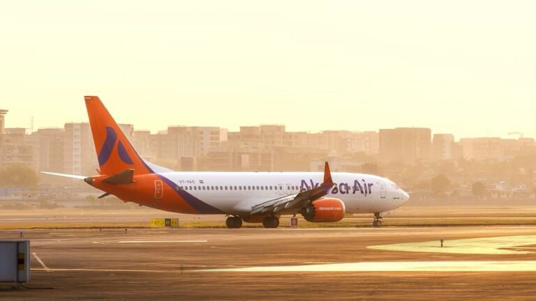 Varanasi, India: A scheduled Akasa Air flight QP 1424, from Varanasi to Bengaluru failed to depart at 7:55 PM on Thursday, leaving 143 passengers stranded overnight in Varanasi following a technical issue. The flight had already been boarded when the problem surfaced. The aircraft was being pushed back from the gate toward the runway when the pilot was alerted to a fault. As a precautionary measure, the pushback was halted and the aircraft returned to the apron for further inspection. The airline’s technical crew attempted repairs for approximately three hours, but the fault could not be fixed. By around 11:30 p.m., the airline announced that the service would not operate. Passengers waited for several hours at the airport before being informed of the cancellation. Subsequently, Akasa Air made arrangements to accommodate the affected passengers in nearby hotels for the night. An Akasa Air spokesperson said “Passengers who chose alternate flight options were provided airport transfers and refreshments. At Akasa Air, passenger safety and comfort are paramount, and we deeply regret the inconvenience caused.” Authorities and airline officials have yet to release a public statement explaining the precise nature of the technical fault. No further updates regarding compensation or rebooking timelines have been formally communicated.