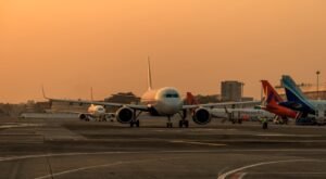 New Delhi, India: ICRA has revised its domestic air passenger growth projection for FY26 to 4–6%, down from the previous estimate of 7–10%. This adjustment follows a modest 0.3% year-on-year increase in passenger traffic to 13.17 million in August 2025. The revised forecast anticipates a total of 172–176 million domestic passengers for the fiscal year, compared to 165.4 million in FY25. International air traffic growth estimates have also been reduced to 13–15% for FY26, from the earlier projection of 15–20%. Factors contributing to this downgrade include geopolitical tensions affecting flight operations, decreased travel confidence following a recent aircraft accident, and global trade challenges such as the impact of U.S. tariffs. Consequently, ICRA projects the aviation sector's net losses to widen to ₹9,500–10,500 crore in FY26, up from ₹5,500 crore in FY25. This increase is attributed to slower passenger growth amid rising aircraft deliveries and operational hurdles. Industry capacity also declined, with capacity deployment in August 2025 dropping 5.8% compared to the same month last year. Supply chain disruptions and engine issues, particularly involving Pratt & Whitney engines, have led to approximately 133 aircraft being grounded as of March 31, 2025, accounting for 15–17% of the total industry fleet. Despite a decrease in aviation turbine fuel (ATF) prices, cost pressures persist due to the dollar-denominated nature of key operating expenses, including fuel, aircraft leases, and maintenance. These factors continue to impact airlines' profitability. ICRA notes that while some carriers benefit from strong parental support and adequate liquidity, others may face challenges in maintaining credit metrics and liquidity profiles in the near term.