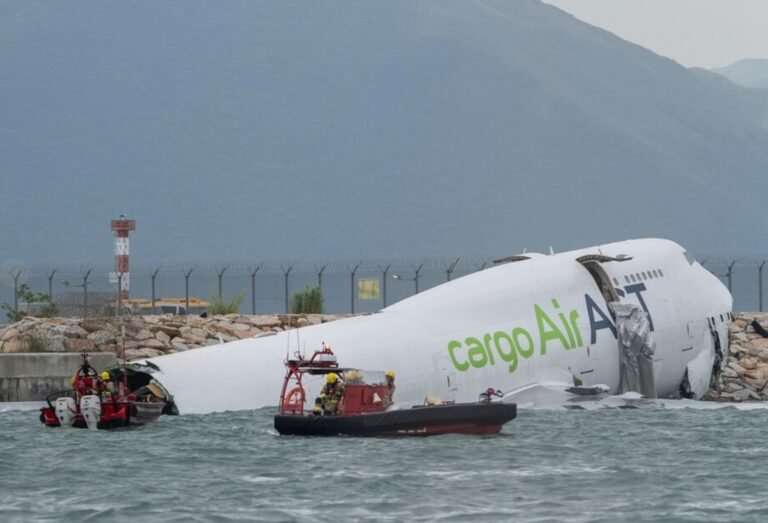 Hong Kong, China: A cargo aircraft operating for Emirates SkyCargo skidded off the north runway at Hong Kong International Airport early Monday, plunging partially into the sea and killing two ground personnel. The four crew members onboard the Boeing 747-400 freighter survived the crash. According to Hong Kong authorities, the accident occurred around 3:50 a.m. local time when the aircraft, identified as TC-ACF, overshot the runway after landing. The plane was operating flight EK9788 from Dubai’s Al Maktoum International Airport on behalf of Emirates SkyCargo. The aircraft is owned and operated by ACT Airlines, a Turkish cargo carrier contracted by Emirates. Initial reports suggest that the aircraft struck a security patrol vehicle positioned near the runway end, forcing the vehicle into the sea. “Both occupants of the vehicle were pulled from the water,” police told Reuters, confirming that one person died at the scene and the other later succumbed to injuries at the hospital. The four Turkish crew members aboard the aircraft were rescued without serious injuries. Photos and videos circulating on social media showed the jet partially submerged near the seawall, with the rear fuselage section visibly damaged. The Airport Authority Hong Kong (AAHK) has temporarily closed the north runway to facilitate investigation and aircraft recovery operations. The airport’s two other runways continue to operate normally. An official investigation has been launched by the Hong Kong Civil Aviation Department. Authorities said they are examining multiple factors, including braking performance, runway conditions, and possible mechanical issues. Early reports indicate that weather conditions were stable at the time of landing, making it unlikely that visibility or wind played a major role. The Boeing 747-400 involved in the accident is 32 years old and had been converted from a passenger aircraft to a freighter several years ago. Emirates confirmed that the flight carried no cargo onboard during the incident. “This tragic incident has claimed the lives of two valued airport workers,” said an Emirates spokesperson, adding that the airline is cooperating fully with local authorities and expressing condolences to the victims’ families.