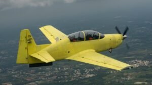 Bangalore, India: In a major milestone for India’s indigenous defence manufacturing, Hindustan Aeronautics Limited (HAL) successfully carried out the maiden flight of the first series-production HTT-40 basic trainer aircraft (tail number TH-4001) from its Bengaluru facility on Friday. The aircraft, built under the “Aatmanirbhar Bharat” initiative, marks the transition of the HTT-40 programme from development to full-scale production. According to HAL, the flight lasted approximately 40 minutes and validated the aircraft’s performance parameters, flight controls, and avionics systems. “This achievement reflects our capability to design, develop, test, and now produce a world-class basic trainer entirely within India,” said HAL Chairman and Managing Director C.B. Ananthakrishnan. “The HTT-40 will soon play a key role in shaping the next generation of Indian Air Force pilots.” The HTT-40 (Hindustan Turbo Trainer-40) is a tandem-seat, fully aerobatic turboprop aircraft designed for ab-initio pilot training. The trainer can perform a range of operations including basic flying, aerobatics, instrument training, and night sorties. Unlike earlier prototypes, the newly flown TH-4001 represents a production-standard version that will lead HAL’s delivery commitments to the Indian Air Force (IAF). The aircraft is powered by a Honeywell TPE331-12B turboprop engine and features a modern glass cockpit, zero-zero ejection seats, hot refuelling capability, and advanced avionics such as VOR/ILS, TACAN, and IFF. HAL officials confirmed that the indigenous content of the HTT-40 currently stands at around 56%, with plans to push it beyond 60% as local suppliers scale up production. The Indian Air Force has placed an order for 70 HTT-40 aircraft, valued at approximately ₹6,800 crore. Deliveries were initially targeted for late 2025 but were delayed due to supply chain constraints, particularly the delayed shipment of Honeywell engines. HAL now expects the first batch of production aircraft to be delivered to the IAF by February 2026, after completion of flight certification and quality assurance trials. A second production line at HAL’s Nashik division has also been inaugurated to accelerate output and meet the IAF’s requirements. The HTT-40 will replace the ageing HPT-32 Deepak trainers that were grounded in 2009 following safety issues. With its modern systems and improved safety standards, the aircraft will serve as the backbone of the IAF’s basic flight training programme, bridging a crucial capability gap in pilot induction.
