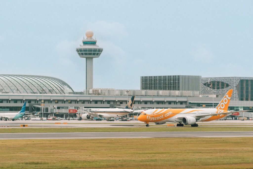 Singapore: Passengers flying out of Changi Airport and Seletar Airport will soon pay a new Sustainable Aviation Fuel (SAF) levy starting in 2026, as part of Singapore’s drive to reduce the aviation sector’s carbon emissions and support global decarbonisation goals. According to the Civil Aviation Authority of Singapore (CAAS), the levy will apply to tickets issued from April 1, 2026, for flights departing on or after October 1, 2026. The collected funds will be channelled into purchasing sustainable aviation fuel, helping airlines transition away from fossil-based jet fuel. Under the new system, passengers will pay different levy rates depending on destination zones and cabin classes: Band 1 – Southeast Asia: Economy S$1 | Premium S$4 Band 2 – Northeast Asia, South Asia, Australia & Papua New Guinea: Economy S$2.80 | Premium S$11.20 Band 3 – Africa, Europe, Middle East, Pacific Islands, Central & West Asia: Economy S$6.40 | Premium S$25.60 Band 4 – The Americas: Economy S$10.40 | Premium S$41.60 Transit passengers passing through Singapore will be exempt from the levy. The scheme will also cover cargo operators, business aviation, and general aviation flights, which will pay a SAF contribution based on aircraft weight or cargo load. CAAS stated that the initiative is a market-based mechanism designed to accelerate the uptake of SAF in a cost-effective and transparent manner. The authority said the levy would make the cost of cleaner fuel predictable for airlines and travellers while ensuring funds are ring-fenced for SAF purchases. “The SAF levy is a key part of Singapore’s decarbonisation framework for aviation. It enables us to make steady progress towards our targets while maintaining competitiveness as a global air hub,” CAAS said in a statement. Singapore’s aviation decarbonisation roadmap targets at least 1 % SAF usage by 2026, increasing to 3 %–5 % by 2030, depending on supply availability and cost developments. The levy rates could be adjusted in future as the SAF blend ratio rises. Globally, sustainable aviation fuel remains more expensive than conventional jet fuel typically costing two to five times more but is widely regarded as the most immediate tool to cut aviation’s carbon footprint. Singapore’s move follows similar measures adopted in the European Union and Japan, and could set a precedent for other Asian hubs exploring SAF mandates or incentives. The initiative complements broader efforts under the International Civil Aviation Organization’s (ICAO) CORSIA framework, which aims for net-zero carbon emissions from international aviation by 2050. By creating a structured and transparent levy system, Singapore aims to send a clear demand signal to fuel producers and investors, potentially attracting SAF production and supply-chain projects to the region.