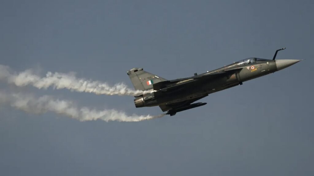Dubai, United Arab Emirates: A HAL Tejas combat fighter aircraft of the Indian Air Force crashed on Friday afternoon during a demonstration sortie at the Dubai Airshow, triggering an immediate response from emergency crews and prompting organisers to suspend flying displays for the day. The crash occurred at approximately 2:10 pm local time at Al Maktoum International Airport, where the biennial event is being held. Witnesses reported seeing the aircraft lose control mid-maneuver before descending rapidly and erupting into flames. Thick black smoke was visible from several parts of the airshow grounds. The Indian Air Force confirmed that the pilot tragically lost his life in the crash. Authorities responded immediately at the scene, and airshow organisers suspended flying displays for the day. The accident follows an online speculation after videos circulated on 18 November 2025, claiming an aircraft had leaked oil during pre-flight ground operations. On 20th November2025, India’s Press Information Bureau, citing technical inputs, dismissed the claims and clarified that the fluid seen in videos was condensed water drained from the aircraft’s Environmental Control System (ECS) and On-Board Oxygen Generating System (OBOGS) both of which routinely expel moisture in hot, humid conditions like Dubai. The Ministry of Defence also termed the online posts “fake”, accusing certain accounts of attempting to discredit the made-in-India fighter. India had positioned the Tejas as a highlight of its participation at the Dubai Airshow, aiming to demonstrate its indigenous fighter programme to potential export customers. The crash is expected to draw scrutiny from aviation regulators, technical evaluators and defence analysts. Experts say the outcome of the investigation particularly whether the cause was mechanical, environmental or pilot-related will influence future display permissions and export prospects. A joint inquiry involving UAE aviation authorities, the Indian Air Force and Hindustan Aeronautics Limited (HAL) is expected to begin shortly. Access to the crash site has been restricted, and debris recovery operations are underway. Airshow organisers briefly halted public movement in open areas after the incident and redirected visitors to indoor exhibition halls. On 12 March 2024, a Tejas light combat aircraft of the Indian Air Force crashed near Jaisalmer in Rajasthan during an operational training sortie, marking the first crash of the indigenous jet in its 23-year history. The pilot ejected safely, and although the aircraft crashed into a building, there were no civilian injuries.