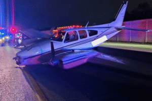Florida, United States: A small twin-engine aircraft was forced to make an emergency landing on the southbound side of Interstate 95 in Brevard County on Monday evening, striking a car in traffic as it descended. The plane identified as a multi-engine Beechcraft 55 came down near mile marker 201 in Cocoa at approximately 5:45 p.m., according to local authorities. The aircraft collided with a 2023 Toyota Camry being driven southbound, causing the car to be crushed against the median and scattering debris across multiple lanes. The Camry’s driver, a 57-year-old woman, was transported to Viera Hospital with what were described as minor injuries. Both the 27-year-old pilot and a 27-year-old passenger aboard the aircraft escaped without injury. Eyewitnesses described a harrowing scene. One bystander, who captured dash-cam footage of the crash, said the plane appeared to “drop out of the sky” and impact the rear of the car before sliding to a halt. Others at the scene including two nurses among passing motorists rushed to assist the driver. Authorities including the Florida Highway Patrol (FHP) and Federal Aviation Administration (FAA) have launched an investigation, with support from the National Transportation Safety Board (NTSB). Preliminary findings indicate the aircraft lost power in both engines before the emergency landing. There are no reports of fuel leaks, and traffic on the interstate which had been blocked in both directions for several hours was restored by around 9 p.m. local time. Officials have appealed to anyone with video footage or additional information to contact the NTSB, as investigators continue their probe into what caused the dual-engine failure. This was the second small-aircraft emergency reported in Florida on December 8. Earlier that afternoon, a Cessna 172 made an emergency landing on Jacobs Road in DeLand, about 46 miles north of Orlando. The single-engine plane came down around 2 p.m., according to reports from Fox 13 News. No major injuries were reported in that incident.