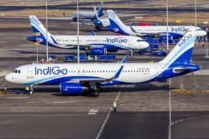 New Delhi, India: India’s largest airline, IndiGo, faced severe operational disruption on Thursday as flight cancellations mounted for a fourth consecutive day, with media reports estimating that cumulative cancellations during the multi-day disruption crossed the 550 flight mark nationwide. The impact was most visible at major airports including Delhi, Mumbai, Ahmedabad and Hyderabad, where nearly 200 flights were cancelled during the day, according to airport-level data. Long queues, missed connections and delayed rebookings were reported across terminals as the airline struggled to stabilise operations. IndiGo issued a public apology for the disruption and said it was working closely with airport authorities and regulators to restore normal schedules and minimise passenger inconvenience. The airline has been grappling with mounting operational stress over the past several days, driven largely by crew availability constraints and scheduling challenges following the implementation of stricter pilot duty and rest norms. Officials said the cascading effect of earlier cancellations further worsened aircraft and crew rotations across the network. Airport-wise data showed that Mumbai alone accounted for 86 cancellations, Bengaluru saw 73, and Delhi recorded over 30 cancellations, highlighting the scale of network-wide disruption at India’s busiest aviation hubs. The multi-day turmoil has left thousands of passengers stranded, with severe delays, missed connections, and cascading operational failures across the carrier’s domestic network. The flight cancellations followed a dramatic collapse in punctuality earlier in the week. On Wednesday, December 3, IndiGo’s on-time performance (OTP) plunged to just 19.7%, its lowest level in years. This marked a steep fall from 35% recorded a day earlier, indicating a rapid deterioration in schedule reliability. With fewer than one in five flights operating on time, IndiGo, once regarded as India’s most punctual airline, saw its reputation for schedule discipline severely eroded within 48 hours. For Thursday, December 4, sustained cancellations, rolling delays and aircraft rotation failures across multiple cities throughout the day indicated that punctuality remained under acute pressure. The crisis has been triggered primarily by an acute shortage of available pilots following the implementation of stricter crew duty and rest regulations. IndiGo underestimated the number of additional pilots required to sustain its high-frequency schedule under the new regulatory framework. As a result, the airline was left with little buffer once the stricter rest rules became enforceable. Once the first wave of cancellations began, the crisis escalated rapidly through cascading operational failures, including aircraft misplacement, delayed crew handovers, disrupted maintenance windows, and congestion at high-density airports. These knock-on effects compounded recovery efforts and caused rolling delays across multiple flight banks through the day. The underlying trigger for the disruption lies in the revised Flight Duty Time Limitation (FDTL) norms introduced by the DGCA, aimed at strengthening aviation safety by reducing fatigue-related risks for pilots. The second and most stringent phase of these rules came into force on November 1, 2025. Under the revised framework, pilots are mandated to receive 48 consecutive hours of weekly rest, face tighter limits on consecutive night duties, and are subject to caps on night landings and duty extensions. While the industry had advance notice of the regulatory changes, IndiGo’s internal staffing preparedness appears to have fallen short. Officials said the airline had operated with a very thin standby crew margin even before the new norms were enforced, leaving it vulnerable to large-scale disruption once pilot availability dropped. With passenger inconvenience mounting and network stability deteriorating, the DGCA has now stepped in to closely supervise IndiGo’s recovery plan. The regulator has directed the airline to submit a detailed mitigation strategy covering crew hiring, training schedules and revised rostering practices. DGCA is planning to grant IndiGo a temporary, conditional waiver from certain pilot rest provisions to arrest further operational collapse. The proposed relief is expected to be short-term and tightly monitored, with compliance milestones linked to crew augmentation and scheduling corrections. The regulator has made it clear that safety standards will not be permanently diluted and that any relaxation will be transitional. IndiGo has informed authorities that it expects phased stabilisation of its network by February 10, 2026, subject to successful induction of additional crew and progressive restoration of flight rotations. The disruption at IndiGo which operates over 2,000 flights daily and carries more than half of India’s domestic air passengers has sent ripples through the aviation sector. While the FDTL norms are widely seen as a necessary safety reform, the crisis has exposed the operational vulnerability of airlines that expand capacity faster than manpower buffers. For passengers, uncertainty is likely to continue in the near term. Aviation officials have advised travellers to monitor flight status closely and exercise refund and rebooking rights in the event of cancellations as IndiGo works to stabilise its schedule.