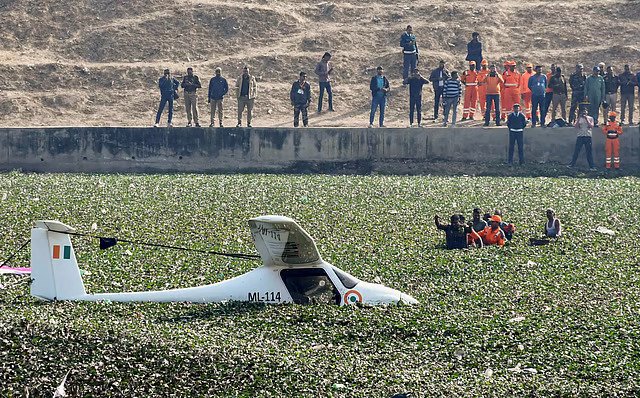 Prayagraj, India: A two‑seater Indian Air Force (IAF) microlight trainer aircraft made an emergency landing into a pond near KP College in Prayagraj on Wednesday afternoon after developing a technical snag mid‑flight, officials and eyewitnesses said. The aircraft, which had departed on a routine training sortie from Air Force Station Bamrauli at approximately 12:15 pm, reportedly lost altitude after a suspected technical malfunction, possibly related to engine failure, according to defence sources and eyewitness accounts. Eyewitnesses said the light trainer circled at low altitude before descending into the water‑hyacinth covered pond behind KP College, generating a loud noise that drew immediate attention from local residents. Local residents were first on the scene and played a critical role in assisting the two pilots out of the shallow, muddy water before formal emergency teams arrived. Police, fire brigade personnel and rescue divers were deployed shortly after the incident was reported. Deputy Commissioner of Police (City) Manish Shandilya confirmed that both crew members escaped without injuries and that there were no reports of civilian casualties or property damage. In a statement released on the IAF’s official social media channels, the Air Force said, “A Microlite aircraft of the IAF, while undertaking a routine sortie, from AF Station Bamrauli near Prayagraj at 1215 hrs on January 21, 2026, experienced a technical malfunction, and was safely force landed in an uninhabited area, ensuring no damage to civil life or property. Both pilots on board are safe.” The IAF further announced that a Court of Inquiry has been ordered to ascertain the exact cause of the malfunction and to review flight records, maintenance logs and pilot reports as part of the formal investigation process. Previous Incidents: In 2025, an Indian Air Force (IAF) Jaguar two-seater fighter jet crashed near Jamnagar, Gujarat, during a night training mission on April 2, 2025, after the aircraft encountered a technical malfunction mid-air, forcing the pilots to eject to safety, officials said. One pilot succumbed to injuries sustained in the incident and was later confirmed dead, while the other was rescued and is undergoing treatment in Jamnagar. The crash occurred in an open field near Suvarda village, about 12 km from Jamnagar city, triggering a fire and scattering wreckage, though there were no civilian casualties or damage to nearby property. The IAF expressed deep regret over the loss, extended condolences to the bereaved family, and announced that a Court of Inquiry has been ordered to determine the exact cause of the accident. Later in the same year, a twin-seater Indian Air Force (IAF) Jaguar trainer aircraft crashed on July 9, 2025, near Bhanuda village in Churu district, Rajasthan, during a routine training sortie, killing both pilots on board, defence officials confirmed. The aircraft, which had taken off from Suratgarh Air Force Base, went down in an agricultural field around mid-afternoon, scattering wreckage across the impact zone, and causing no reported damage to civilian property.
