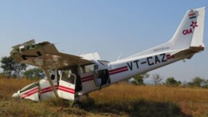 Dhana, India: A preliminary investigation report released by India’s Aircraft Accident Investigation Bureau (AAIB) has detailed how a Cessna 172S training aircraft operated by Chimes Aviation Pvt. Ltd. crashed during a go-around at Dhana Airstrip in Madhya Pradesh on December 10, 2025, leaving a 22-year-old trainee pilot with minor injuries and destroying the aircraft. The aircraft, registered VT-CAZ, was returning from a solo cross-country training flight when the accident occurred at 08:43 UTC (2:13 pm IST) while attempting to land on Runway 35. According to the AAIB, the trainee pilot made an initial approach but aborted the landing due to instability. During a second approach, the aircraft floated beyond the touchdown zone, prompting air traffic control to order another go-around. As the pilot advanced power, the aircraft pitched up abruptly, rolled left, and lost control, crashing onto the unpaved ground beside the runway. The pilot managed to unbuckle and escape from the wreckage. No fire broke out, but the aircraft sustained substantial damage, including shattered propeller blades, collapsed nose landing gear, broken windscreens, and bent wings. The trainee pilot held a valid Student Pilot License, had 74.5 flying hours, all on the Cessna 172, and had been medically cleared and well rested before the flight. A breath-analyser test conducted before departure was also normal. The aircraft, built in 2014, had a valid airworthiness certificate and had completed a 50-hour maintenance inspection just one day before the accident, on 9 December 2025, with no defects reported. Weather conditions were also favourable, with clear skies, 6 km visibility, and light winds, ruling out bad weather as a contributing factor. AAIB teams have secured the wreckage and recovered Garmin G1000 flight data, CCTV recordings, and engine and airframe components for detailed analysis. Fuel and oil samples are also being tested. Because the aircraft and key components were manufactured overseas, the US National Transportation Safety Board (NTSB) and Germany’s Federal Bureau of Aircraft Accident Investigation (BFU) have been notified and are assisting the Indian investigation. The AAIB stressed that the findings are preliminary and aimed only at preventing future accidents, not assigning blame. A final report will determine the root cause of the loss of control during the go-around.