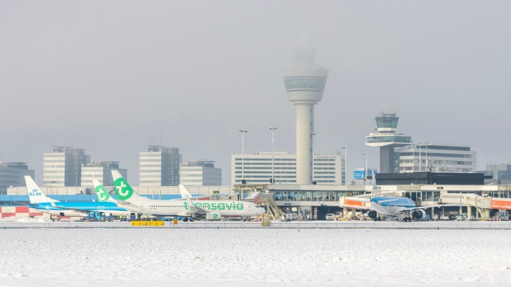 Amsterdam, Netherlands: Amsterdam Schiphol Airport saw a sharp reduction in flight cancellations for Thursday as the prolonged winter storm that crippled Europe’s busiest hub for air travel showed signs of easing, though delay risks remain and residual disruption persists. Airlines and airport officials reported only a small number of scheduled flights affected for 8 January, marking a significant improvement from the previous days of winter chaos that saw hundreds of flights scrapped daily. Officials from Schiphol and Dutch flag carrier KLM Royal Dutch Airlines confirmed that around 60 inbound services scheduled for Thursday had been cancelled by late Wednesday afternoon, largely due to aircraft being unable to return after cancellations earlier in the week. Only a handful of departing flights have been removed from the Thursday schedule. In total, six departures out of 565 scheduled Thursday flights were cancelled by various carriers, and approximately 30 incoming flights were expected to experience delays of varying durations. A spokesperson for Schiphol emphasised that weather conditions were expected to be milder than earlier in the week, and that airlines “do not expect as many cancellations as in recent days”. However, passengers were urged to plan for delays and to check flight status before arriving at the airport. The airport’s operational challenges began on 2 January 2026, when persistent snowfall, strong winds and freezing conditions first caused widespread cancellations. Over the following days, airlines cancelled around 3,500 scheduled flights at Schiphol on average hundreds per day as snow and ice compounded staffing and logistical issues. On 7 January, more than 700 flights were cancelled, again due to heavy snow and high wind, leaving long lines of stranded passengers and disrupted connections across Europe. A major factor behind the cancellation surge was the strain on de‑icing operations. KLM, responsible for most de‑icing services at Schiphol, reported that its supplies of glycol‑based de‑icing fluid were running critically low after days of continuous usage, prompting emergency procurement efforts from suppliers in Germany. Airport ground crews worked around the clock to clear runways and taxiways, but continuous snowfall and freezing precipitation created persistent bottlenecks that reduced the airport’s capacity to handle arriving and departing flights. Travelers faced lengthy delays and cancellations through the week, with many spending nights in airport terminals. Schiphol staff provided cots, blankets, food and beverages for those unable to depart. Although Thursday’s forecast suggests fewer cancellations than earlier in the week, weather warnings including Code Yellow alerts for freezing rain and sleet remained in place for the Netherlands, raising the possibility of renewed disruption, particularly if conditions deteriorate over the coming days.