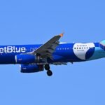 JetBlue Flight Makes Emergency Return After Engine Issue, Smoke Reported In Cockpit SEO DES: No injuries among 122 onboard; one passenger treated for chest pain. Airport operations were briefly suspended, ground stop lifted around 7 p.m SOCIAL: Two separate aviation incidents in the United States on Wednesday prompted emergency returns and federal investigations. In Newark, a JetBlue Airbus A320 bound for West Palm Beach made an emergency return after an engine issue and smoke were reported in the cockpit, leading to an evacuation of 122 passengers and crew. No injuries were reported, though one passenger was treated for chest pain, and airport operations were briefly suspended before a ground stop was lifted around 7 p.m. In a separate incident in Houston, a Delta Air Lines flight returned shortly after takeoff due to an unruly passenger who attempted to approach the cockpit. The passenger was detained by police upon landing, and the flight later continued to Atlanta with a delay. The FAA is investigating both incidents. Image: 4300streetcar (Wikimedia) Video: JetBlue Newark, United States: A JetBlue Airways flight bound for West Palm Beach, Florida, made an emergency return to Newark Liberty International Airport on Wednesday evening after experiencing an engine failure and smoke in the cockpit, prompting the evacuation of all passengers and temporary disruption of airport operations. JetBlue Flight 543, operated on an Airbus A320, departed Newark at approximately 5:45 p.m. local time, but returned to the airport shortly after takeoff when the crew reported a significant mechanical problem, officials said. After landing safely and taxiing off the runway, the flight crew reported smoke in the cockpit and cabin. Federal Aviation Administration (FAA) personnel directed an emergency evacuation of passengers and crew via the aircraft’s emergency slides onto a taxiway. Officials confirmed that no injuries were reported among the 122 passengers and crew members, though one passenger was briefly treated for chest pains at a local hospital. The aircraft was subsequently removed from the taxiway to allow normal operations to resume. Airport authorities temporarily suspended flights inbound and outbound, issuing a ground stop that was lifted by around 7 p.m. local time. The Port Authority of New York and New Jersey, which operates Newark Liberty International Airport, and the FAA did not immediately disclose the precise cause of the engine failure. The FAA confirmed an investigation into the incident is underway. In an official statement following the incident, JetBlue emphasized that safety remains its highest priority, adding it is working closely with federal authorities as they review the sequence of events. The emergency landing and subsequent evacuation briefly disrupted flight operations at one of the United States’ busiest aviation hubs. According to traffic tracking data, approximately 31% of arriving flights and 30% of departures at Newark were delayed during the disruption. Airport authorities urged travelers to check with their airlines for the latest flight status information due to the ripple effects of the incident on scheduling and ground operations. In a separate incident on Wednesday morning, Delta Air Lines Flight 2557, scheduled to depart from William P. Hobby Airport for Hartsfield-Jackson Atlanta International Airport, was forced to return shortly after takeoff due to an unruly passenger whose actions prompted a police response. According to law enforcement and airline officials, the flight carrying 85 passengers and five crew members lifted off at about 5:25 a.m. local time when a passenger began exhibiting “unruly and unlawful behavior,” including physical confrontations with others onboard. The Houston Police Department was alerted after air traffic controllers reported that the individual attempted to approach the cockpit. While initial reports suggested a possible breach attempt, Delta Air Lines later clarified that the passenger did not make contact with or access the flight deck. The aircraft returned safely to Hobby Airport by around 5:40 a.m., where officers detained the male passenger without further incident. No serious injuries were reported. After the situation was resolved, the flight resumed service and later arrived in Atlanta approximately 90 minutes behind schedule. The Federal Aviation Administration (FAA) has confirmed it will investigate.