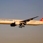 Turkish Airlines TK75 Diverts To Vienna After Mid-Air Emergency Declaration SEO DES: The Boeing 777 diverted about two hours into the flight and landed safely in Vienna, The airline has not yet confirmed the cause of the emergency SOCIAL: Turkish Airlines Flight TK75 from Istanbul to Vancouver made an emergency landing in Vienna on 26 February 2026 after the crew declared a general in-flight emergency and transmitted a 7700 squawk code. The Boeing 777-300ER (TC-LJJ) diverted about two hours into the flight and landed safely with no reported injuries. The airline has not yet disclosed the cause of the emergency, and further updates are awaited. Air traffic controllers provided priority handling and cleared surrounding traffic to ensure a safe approach. Airport emergency services remained on standby as a precaution during the landing. Passengers are expected to be re-accommodated subject to technical inspections and operational clearance. Image: byeangel (Flickr) Video: Turkish Airlines Vienna, Austria: A long-haul Turkish Airlines flight en route from Istanbul, Turkey, to Vancouver, Canada, made an unscheduled emergency landing at Vienna International Airport on Thursday, 26 February 2026, after the flight crew declared a general in-flight emergency over European airspace, according to flight tracking data reports. Turkish Airlines Flight TK75, operated by a Boeing 777-300ER registered as TC-LJJ, departed Istanbul Airport (IST) in the early afternoon and was approximately two hours into the scheduled 12-hour transatlantic journey when the aircraft began an abrupt diversion toward Austria. About 13:00–13:15 UTC, the flight crew transmitted the internationally recognised “squawk 7700” emergency transponder code, signalling a general emergency and requesting priority handling from air traffic control. Controllers cleared surrounding traffic and guided the aircraft toward Vienna as the closest major airport capable of accommodating a fully loaded wide-body aircraft under emergency conditions. Vienna International Airport’s emergency services including fire, medical and rescue units were placed on alert as a precautionary response while the flight executed a controlled descent.The aircraft landed safely, and there were no immediate reports of injuries among passengers and crew. Turkish Airlines had not publicly released an official statement detailing the specific cause of the emergency. The 7700 transponder code covers a wide range of possible scenarios, from technical malfunctions to medical incidents or other operational irregularities; it does not indicate the precise nature of the problem. As investigations continue and official updates from Turkish Airlines or Austrian authorities emerge, further details on the cause of the emergency and the subsequent operational impact on the flight’s onward journey and passenger arrangements are expected.