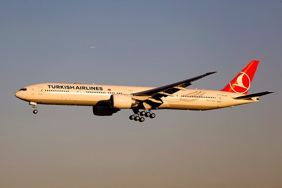 Turkish Airlines TK75 Diverts To Vienna After Mid-Air Emergency Declaration SEO DES: The Boeing 777 diverted about two hours into the flight and landed safely in Vienna, The airline has not yet confirmed the cause of the emergency SOCIAL: Turkish Airlines Flight TK75 from Istanbul to Vancouver made an emergency landing in Vienna on 26 February 2026 after the crew declared a general in-flight emergency and transmitted a 7700 squawk code. The Boeing 777-300ER (TC-LJJ) diverted about two hours into the flight and landed safely with no reported injuries. The airline has not yet disclosed the cause of the emergency, and further updates are awaited. Air traffic controllers provided priority handling and cleared surrounding traffic to ensure a safe approach. Airport emergency services remained on standby as a precaution during the landing. Passengers are expected to be re-accommodated subject to technical inspections and operational clearance. Image: byeangel (Flickr) Video: Turkish Airlines Vienna, Austria: A long-haul Turkish Airlines flight en route from Istanbul, Turkey, to Vancouver, Canada, made an unscheduled emergency landing at Vienna International Airport on Thursday, 26 February 2026, after the flight crew declared a general in-flight emergency over European airspace, according to flight tracking data reports. Turkish Airlines Flight TK75, operated by a Boeing 777-300ER registered as TC-LJJ, departed Istanbul Airport (IST) in the early afternoon and was approximately two hours into the scheduled 12-hour transatlantic journey when the aircraft began an abrupt diversion toward Austria. About 13:00–13:15 UTC, the flight crew transmitted the internationally recognised “squawk 7700” emergency transponder code, signalling a general emergency and requesting priority handling from air traffic control. Controllers cleared surrounding traffic and guided the aircraft toward Vienna as the closest major airport capable of accommodating a fully loaded wide-body aircraft under emergency conditions. Vienna International Airport’s emergency services including fire, medical and rescue units were placed on alert as a precautionary response while the flight executed a controlled descent.The aircraft landed safely, and there were no immediate reports of injuries among passengers and crew. Turkish Airlines had not publicly released an official statement detailing the specific cause of the emergency. The 7700 transponder code covers a wide range of possible scenarios, from technical malfunctions to medical incidents or other operational irregularities; it does not indicate the precise nature of the problem. As investigations continue and official updates from Turkish Airlines or Austrian authorities emerge, further details on the cause of the emergency and the subsequent operational impact on the flight’s onward journey and passenger arrangements are expected.
