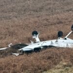 Littleborough, United Kingdom: Two men have died after a private light aircraft crashed in farmland near Littleborough, in the Rochdale district of Greater Manchester, police confirmed on Tuesday. Greater Manchester Police (GMP) said emergency services were called to reports of the incident shortly after 11 a.m. GMT on 3 February 2026. The crash occurred in a rural area close to Hollingworth Lake and Blackstone Edge, not far from the M62 motorway. Officers and paramedics quickly arrived on scene, supported by fire crews and specialist investigators from the Air Accidents Investigation Branch (AAIB). GMP confirmed the bodies of two men were found at the site and were pronounced dead by emergency responders. Preliminary data from flight-tracking services indicate the aircraft involved was a Cirrus SR20, a single-engine four-seat light aircraft commonly used in private and general aviation. The plane had reportedly departed Birmingham Airport’s XLR Executive Jet Centre at around 10 a.m. on Tuesday. It was tracked flying for approximately 40 minutes before its transponder signal stopped south of the M62 near Marsden, West Yorkshire, shortly before the crash. There were no other passengers on board, and there have been no confirmed injuries on the ground. Police established a secure perimeter around the crash site while emergency personnel conducted searches and evidence recovery. Road closures were in place in the immediate vicinity, and residents and visitors were asked to avoid the area to allow investigative work to continue. Images circulating on social media and confirmed by official statements show a yellow parachute canopy entangled on an electricity pylon near the scene. The Cirrus aircraft type involved is fitted with a Ballistic Recovery System (BRS), designed to deploy a whole-aircraft parachute in emergencies. At this stage, investigators have not provided a definitive explanation of whether the parachute was deliberately deployed by the pilot or triggered by impact forces. A National Grid spokesman said its engineers were on site supporting the emergency services, and there was no disruption to the local power supply. Chief Superintendent Danny Inglis, district commander for GMP’s Rochdale division, described the incident as “a devastating incident where two people have lost their lives,” and extended condolences to the families and friends of the deceased. He added that officers would remain at the scene into the following days to support investigators and collect evidence. The AAIB confirmed that it has launched a formal investigation into the accident and has deployed a multidisciplinary team of inspectors to examine wreckage, flight data, and other relevant materials. The regulatory body typically issues a preliminary report in the weeks following an accident and a full report in due course, depending on the complexity of the findings.