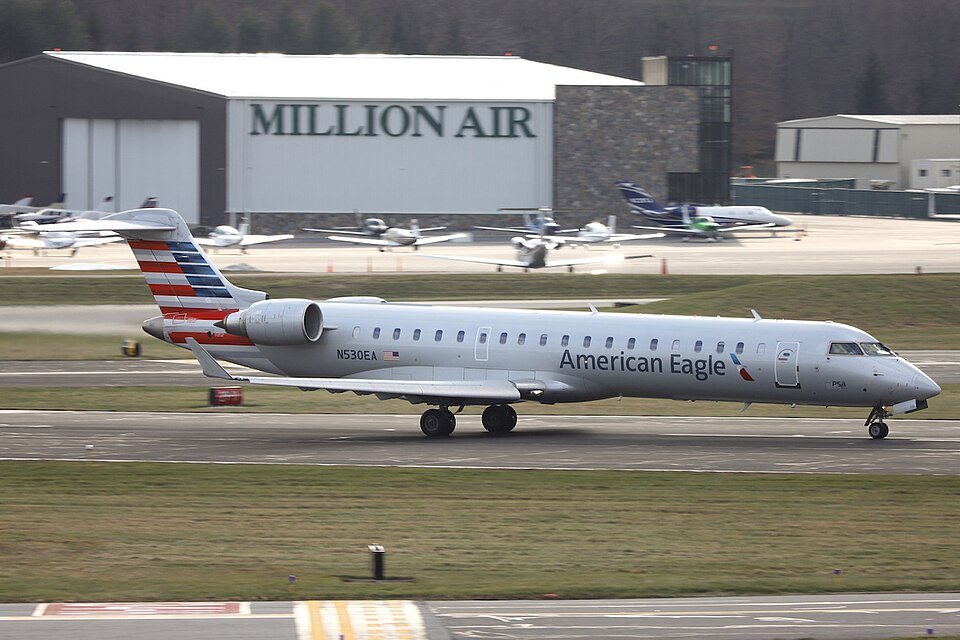 American Eagle Flight Returns To Raleigh-Durham Airport After Smoke Alert Mid-Air SEO DES: Passengers evacuated with no injuries, American Airlines cited a “reported odor”; aircraft grounded for inspection, cause still under investigation SOCIAL: An American Eagle CRJ-900 flight returned to Raleigh-Durham International Airport shortly after takeoff due to reported smoke and a burning odor in the cabin. The aircraft landed safely within 23 minutes, with emergency services on standby. Passengers were evacuated and no injuries were reported. American Airlines said the diversion was due to a “reported odor,” and the aircraft was taken out of service for inspection, with the exact cause yet to be determined. Image: Quintin Soloviev (Wikimedia) Video: American Airlines Morrisville, United States: An American Eagle regional flight was forced to return to Raleigh-Durham International Airport shortly after takeoff on Monday night after pilots reported smoke and a burning odor inside the aircraft cabin, prompting an emergency response. American Eagle Flight 5201, operated by a Bombardier CRJ-900, departed Raleigh-Durham International Airport (RDU) at approximately 8:13 p.m. en route to Philadelphia. Within minutes of departure, the flight crew detected what was described as smoke accompanied by a burning smell inside the cabin, triggering standard emergency procedures. Following the detection, pilots elected to discontinue the climb and remain in the vicinity of the airport while preparing for a safe return. Flight tracking and local reports indicate the aircraft maneuvered over northern Wake County, executing turns over Falls Lake and later looping near Jordan Lake to align for landing. The aircraft landed safely at RDU approximately 23 minutes after departure under emergency conditions. Emergency services, including fire crews and EMS units, were positioned on standby as the aircraft touched down. Visuals from the airport showed the aircraft surrounded by emergency vehicles shortly after landing. Passengers were evacuated onto the tarmac and transported to the terminal by buses. No injuries were reported among passengers or crew. American Airlines confirmed that the flight returned to RDU due to a “reported odor” onboard, a term commonly used in aviation when the exact source of smoke or fumes has not yet been identified. The aircraft was subsequently taken out of service for a detailed inspection by maintenance teams. “All passengers made it safely to the terminal, and we are working to assist them with their travel plans,” the airline said, apologizing for the disruption and commending the crew’s handling of the situation. As of now, no confirmed cause of the smoke or odor has been officially released.