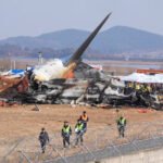 Jeju Air Crash Probe Finds Airport Structure May Have Worsened Deadly 2024 Disaster SEO DES: Investigators say the structure failed international standards requiring frangible supports, suggesting the crash might have been survivable otherwise SOCIAL: Investigations into the December 2024 crash of Jeju Air Flight 2216 at Muan International Airport, South Korea, have linked the disaster to longstanding airport infrastructure safety failures. The Boeing 737-800 belly-landed after a suspected bird strike but overran the runway and struck a rigid concrete embankment supporting a navigation localiser antenna, causing a catastrophic fire that killed 179 of the 181 people on board. Investigators say the structure did not meet international safety standards requiring frangible supports that break on impact, suggesting the crash may have been survivable otherwise. South Korea’s government has acknowledged the safety lapse, launched an independent inquiry, and begun reviewing runway infrastructure nationwide while a final investigation report is expected in 2026. Image: Aero Time Video: TOI Muan, South Korea: Investigations into the 2024 crash of a Jeju Air passenger jet in South Korea have revealed that longstanding airport infrastructure failures likely played a critical role in turning a survivable emergency landing into the country’s deadliest aviation disaster. Jeju Air Flight 2216, a Boeing 737-800 operating from Bangkok to Muan, crashed at Muan International Airport on 29 December 2024, killing 179 of the 181 people on board. Only two cabin crew members survived the accident. Recent findings cited in a government-commissioned report suggest that the aircraft’s occupants may have survived if the plane had not collided with a rigid concrete structure located at the end of the runway. The aircraft had belly-landed during an emergency approach and slid beyond the runway before striking a concrete mound supporting a navigation localiser antenna, triggering a catastrophic fire. The concrete embankment that the aircraft struck has become a central focus of the investigation. Structural simulations conducted after the accident indicated that the impact with the runway overrun itself was survivable and that the aircraft could have come to a halt with far fewer casualties if the structure had been designed to break on impact. Experts and lawmakers have argued that the structure did not meet international aviation safety standards, which typically require runway navigation equipment to be mounted on “frangible” supports designed to collapse during an aircraft collision. South Korea’s transport authorities later acknowledged that the embankment contributed to the severity of the crash and announced plans to remove or redesign similar structures at several airports across the country. Opposition lawmakers have also blamed decades of government negligence, noting that the problematic structure had existed since the late 1990s without corrective action despite safety concerns. Investigators believe the emergency landing was triggered by a bird strike during the aircraft’s final approach. Remains of birds were found in both engines during the preliminary investigation. Evidence later indicated that the pilots may have inadvertently shut down the less-damaged engine after the bird strike, potentially reducing available thrust during the emergency landing attempt. The aircraft ultimately landed without deploying its landing gear and slid along the runway before colliding with the concrete structure at the runway’s end, leading to an explosion and fire that destroyed the aircraft. The disaster has triggered widespread criticism of the investigation process and government oversight of aviation safety. Families of the victims have accused authorities of delaying reports and failing to provide transparency about the causes of the crash. In response to mounting pressure, South Korea’s parliament approved an independent inquiry to examine the accident, including the role of bird strikes, possible mechanical failures, and the runway structure that the aircraft struck. South Korea’s Transport Ministry has also acknowledged that a navigation structure at Muan International Airport failed to meet safety standards, contributing to the deadly crash of a Jeju Air Boeing 737-800 in December 2024. Authorities admitted the structure should have been designed to break on impact, in line with international safety guidelines, and its rigid construction likely worsened the disaster. A final report from investigators is expected in 2026, as officials continue to analyze flight data, cockpit recordings and infrastructure safety standards. The tragedy remains the deadliest aviation accident in South Korean history and has prompted a nationwide review of runway safety areas and navigation equipment installations at airports across the country.