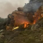 Firefighting Helicopter Crashes In Hout Bay During Wildfire Operations, Pilot Survives SEO DES: The aircraft likely struck terrain during water-dropping operations; the pilot survived with injuries, as crews managed the crash site and secondary fire SOCIAL: A firefighting helicopter crashed over Hout Bay in Cape Town, South Africa on 25 March 2026 while battling a wildfire in Table Mountain National Park. The aircraft likely struck mountainous terrain during water-dropping operations. The pilot survived with injuries, and no fatalities were reported. Emergency teams responded swiftly, managing both the crash site and a secondary fire. The wildfire, which began a day earlier, burned around 160 hectares, prompting trail closures, while authorities have launched an investigation into the incident. Cape Town, South Africa: A firefighting helicopter operating over the slopes of Hout Bay in Table Mountain National Park crashed on the evening of 25 March 2026 while assisting efforts to contain a rapidly spreading wildfire, authorities confirmed. The aircraft, contracted to support firefighting operations coordinated by South African National Parks, went down in mountainous terrain between Hout Bay and Constantia Nek during active aerial suppression efforts. Preliminary reports indicate the helicopter encountered difficulty while conducting water-dropping operations over the fire zone. Officials stated that the aircraft likely clipped the mountainside with its main rotor before crashing. Witness accounts and local authorities reported that the helicopter descended shortly after impact, with flames and smoke visible at the crash site. The pilot survived the crash, with reports consistently confirming that no fatalities occurred. Initial updates indicated the pilot was rescued alive with injuries. Authorities described the survival as remarkable given the challenging terrain and operational conditions. A large-scale emergency response was immediately activated, involving: Wilderness Search and Rescue (WSAR) SANParks Kishugu Aviation Netcare24 City of Cape Town Fire and Rescue Services Local law enforcement units Rescue teams were deployed to access the mountainous crash site, while an Incident Management Team was established to coordinate operations and secure the area. Authorities also managed a secondary fire triggered by the crash, as firefighting operations continued in the surrounding area. The helicopter had been actively engaged in combating a wildfire that ignited on 24 March 2026 along the Hout Bay slopes. The blaze spread across mountainous terrain between Hout Bay and Constantia Nek Approximately 160 hectares of vegetation were affected Strong winds contributed to flare-ups and fire spread Multiple aerial assets, including helicopters and fixed-wing aircraft, had been deployed to support ground firefighting crews. As a precaution, authorities closed hiking trails and access routes in the affected areas to ensure public safety and allow uninterrupted firefighting operations. SANParks confirmed that an investigation has been launched to determine the exact cause of the crash. In an official statement, the agency said it is unable to provide further details at this stage as inquiries remain ongoing.