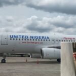 United Nigeria Grounds Two Aircraft After Jet Blast Damage & Bird Strike Incident SEO DES: No injuries reported; aircraft grounded for checks. Back-to-back incidents disrupted operations, causing delays and cancellations network-wide SOCIAL: United Nigeria Airlines faced disruptions after two incidents on March 29, 2026 a jet blast at Murtala Muhammed International Airport damaged a parked Embraer 190 when a baggage trolley was blown into it. While a separate Airbus A320 suffered a bird strike on an Asaba–Lagos flight. Both aircraft were grounded for safety checks, leading to delays and cancellations across the airline’s network. The airline confirmed no injuries and reiterated that all actions were taken in line with strict safety protocols. Lagos, Nigeria: United Nigeria Airlines faced significant operational disruption after two separate incidents, a jet blast-induced ground accident and a bird strike forced the airline to withdraw two aircraft from service within hours on March 29, 2026. According to a travel advisory issued by the airline, the first incident occurred at Murtala Muhammed International Airport, Lagos, involving an Embraer 190 aircraft that had earlier arrived from Akanu Ibiam International Airport as Flight UN0503. The aircraft was parked at the domestic terminal in an open bay between two other aircraft and was being prepared for its next scheduled service, Flight UN0500. During this time, multiple aircraft movements took place simultaneously on the ramp. The airline explained that while one nearby aircraft had begun taxiing after completing boarding, another aircraft was executing a pushback onto the taxiway. The combined movements generated a powerful jet blast in the ramp area. The force of the jet blast displaced ground handling equipment, specifically a baggage trolley, which was blown into the parked Embraer 190. The impact caused damage to critical external components, including the antenna and the forward fuselage near the nose landing gear. Following the incident, the aircraft was immediately withdrawn from service for comprehensive inspection in line with safety protocols, the airline said. In a separate development on the same day, the airline reported a bird strike involving an Airbus A320 operating Flight UN0509 from Asaba to Lagos. The incident occurred during the flight when a bird struck one of the aircraft’s engines. The airline did not report any injuries, but confirmed that the affected aircraft was also grounded for detailed checks and maintenance as a precautionary measure. United Nigeria Airlines stated that the back-to-back incidents led to disruptions across its network, with several flights delayed or cancelled. The airline apologised to passengers, noting that teams were working to minimise the impact and assist affected travellers. The airline emphasised that both decisions to withdraw the aircraft were guided by its “strict and uncompromising safety standards,” reaffirming its commitment to operational safety despite the disruptions.