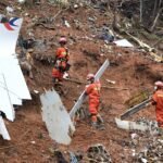 Wuzhou, China: The Boeing 737-800 aircraft, operating a routine domestic service from Kunming to Guangzhou on March 21, 2022, was carrying 132 people, including 123 passengers and nine crew members. About an hour into the flight, while cruising at altitude, the aircraft suddenly entered a steep and rapid descent before plunging almost vertically into a mountainous, forested area in Guangxi. All 132 occupants were killed, and no survivors were found, marking China’s deadliest air crash. China’s aviation regulator, the Civil Aviation Administration of China, launched an investigation immediately after the crash, dispatching emergency teams to the remote impact site. Due to the aircraft’s U.S. manufacture, the investigation also involved international participants, including the National Transportation Safety Board, Boeing, and the Federal Aviation Administration, who provided technical assistance. A major breakthrough in the early phase of the investigation came with the recovery of both flight recorders. The cockpit voice recorder was located on March 23, 2022, followed by the flight data recorder, which was retrieved from deep within the crash debris days later. Both devices were severely damaged due to the high-impact crash and required detailed forensic analysis, including data extraction overseas. Preliminary examination of the data indicated that the aircraft descended rapidly from around 29,000 feet, briefly stabilized, and then entered a final near-vertical dive. Air traffic controllers attempted to contact the pilots multiple times during the descent, but no distress call was made and no response was received from the cockpit. In its preliminary report released in April 2022, the CAAC ruled out several common causes of aviation accidents. Investigators found no evidence of mechanical failure, adverse weather conditions, or dangerous cargo. The aircraft was deemed airworthy and properly maintained, while the flight crew were found to be qualified, adequately rested, and medically fit. Follow-up updates issued in 2023 and 2024 reiterated these findings, stating that no abnormalities had been identified in the aircraft systems, flight operations, or air traffic control procedures. Despite these findings, investigators have not been able to establish a definitive cause of the crash. A report published in 2022 by The Wall Street Journal, citing U.S. officials familiar with black box analysis, suggested that the aircraft may have been intentionally put into a dive from the cockpit. However, Chinese authorities have not confirmed this interpretation and have cautioned against speculation, warning that unverified conclusions could mislead the public and interfere with the investigation. Under international aviation standards set by the International Civil Aviation Organization, accident investigations are expected to produce an initial report within 30 days and a final report within one year wherever possible. In the case of MU5735, a preliminary report was issued within the required timeframe, but no final report has been released even after four years. The last official update from Chinese authorities came in March 2024, with no substantive developments disclosed since then. The prolonged delay has drawn attention from global aviation bodies, including the International Air Transport Association, which has emphasized the importance of timely accident reports in improving aviation safety worldwide. As of 2026, the investigation into Flight MU5735 remains officially ongoing. No confirmed cause has been identified, and no comprehensive final report has been made public.