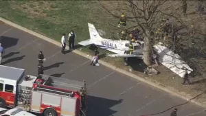 Flight Instructor And Student Injured In Northeast Philadelphia Training Flight Crash SEO DES: The aircraft operated by Fly Legacy Aviation crashed after an engine failure during a routine lesson. Both onboard survived with non-life-threatening injuries SOCIAL: A training aircraft operated by Fly Legacy Aviation crashed in Northeast Philadelphia on April 1 after an engine failure during a routine lesson, injuring an instructor and a student pilot identified as an off-duty police officer. The instructor attempted an emergency return, but the aircraft clipped a tree and crashed into Fluehr Park. Both occupants survived with non-life-threatening injuries, no one on the ground was hurt, and authorities, including the Federal Aviation Administration and National Transportation Safety Board, have launched an investigation. Philadelphia, United States: A training aircraft operated by a local flight school crashed in a residential park in Northeast Philadelphia on April 1, injuring two people onboard a flight instructor and a student pilot after an attempted emergency landing went wrong. The aircraft, identified as a Piper PA-28 (Pilot 100i), was being used for a routine instructional flight by Fly Legacy Aviation, a Philadelphia-based flight training academy. The flight had departed from Northeast Philadelphia Airport shortly before the incident. Authorities confirmed that the student pilot was the off-duty officer. Both occupants survived the crash and were transported to hospital. Officials stated they were conscious and alert, though they sustained serious but non-life-threatening injuries. Preliminary findings indicate the aircraft experienced a loss of engine power mid-flight, reportedly while flying over or near the Delaware River. The instructor initiated emergency procedures and attempted to return toward the airport. However, during the descent, the aircraft clipped a tree, lost stability and spun before crashing into Fluehr Park, a public park surrounded by residential homes. Emergency responders reached the scene quickly. Despite a minor fuel leak, no fire broke out. Authorities confirmed, no injuries on the ground and no structural damage to nearby homes Officials noted the outcome could have been significantly worse given the densely populated neighborhood surrounding the crash site. Eyewitnesses described a sudden loss of altitude before impact. One local resident told the media the aircraft appeared to be “coming down fast and struggling to stay level.” Police officials confirmed that one of the injured individuals was an off-duty officer and stated that both victims were “extremely fortunate to survive” given the nature of the crash. Emergency responders, including police and fire crews, secured the area and assisted in extraction and evacuation. The Federal Aviation Administration (FAA) and the National Transportation Safety Board (NTSB) have launched a formal investigation.