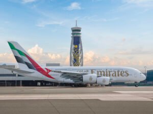 Emirates Launches Construction Of $5.1 Billion Mega Aircraft Engineering Hub In Dubai SEO DES: The 1.1 million sqm complex will feature huge hangars, logistics hubs, training centres, workshops and the world’s largest landing gear facility SOCIAL: Emirates has begun construction of a US$5.1 billion mega engineering and MRO complex at Dubai South near Al Maktoum International Airport. Announced on May 18, 2026, the project will become one of the world’s largest and most advanced aircraft maintenance facilities, capable of handling 28 widebody aircraft simultaneously. Spanning 1.1 million square metres, the development will include massive hangars, logistics centres, training facilities, workshops and the world’s largest dedicated landing gear facility. The project supports Emirates’ long-term fleet expansion plans and Dubai’s vision of becoming a global aviation and engineering hub. Dubai, United Arab Emirates: Dubai-based carrier Emirates has officially launched construction of a massive US$5.1 billion engineering and maintenance complex at Dubai South, marking one of the largest aviation infrastructure investments ever undertaken by a commercial airline. The groundbreaking ceremony took place on Monday, May 18, 2026, at Dubai South near Al Maktoum International Airport (DWC). The project is designed to become the world’s most advanced aircraft maintenance, repair and overhaul (MRO) facility and forms a major part of Dubai’s long-term aviation expansion strategy. The facility will support Emirates’ future fleet growth while strengthening Dubai’s position as a global aviation engineering hub. The ceremonial groundbreaking was attended by His Highness Sheikh Ahmed bin Saeed Al Maktoum, Chairman and Chief Executive of Emirates Airline and Group; Sir Tim Clark, President of Emirates Airline; His Excellency Khalifa Al Zaffin, Executive Chairman of Dubai Aviation City Corporation and Dubai South; and Dai Hegen, Chairman of China Railway Construction Corporation Limited (CRCC). According to Emirates, the mega-facility will span approximately 1.1 million square metres, making it one of the largest buildings in the world by volume and the largest steel structure in the Gulf Cooperation Council region. One of the project’s most notable features is a hangar complex capable of servicing 28 widebody aircraft simultaneously, including the airline’s Airbus A380 and Boeing 777 fleets. Emirates stated that the development will also include two state-of-the-art aircraft paint hangars with capacity to handle both widebody and narrowbody aircraft. The engineering complex will house the world’s largest dedicated landing gear workshop and the world’s largest free-span aircraft hangar measuring 285 metres wide. The project will additionally feature around 77,000 square metres of maintenance workshop space and approximately 380,000 square metres dedicated to logistics and storage operations. Emirates also confirmed that the facility will include a dedicated administrative headquarters for Emirates Engineering comprising around 50,000 square metres of office space along with 15,000 square metres allocated for technical training and workforce development. A dedicated gateway facility controlling airside access will also be constructed as part of the wider complex. The project is being delivered by China Railway Construction Corporation, while French engineering consultancy Artelia has been appointed as project consultant. Speaking during the ceremony, Sheikh Ahmed bin Saeed Al Maktoum described the investment as a “strategic step forward” for Dubai’s aviation ambitions, emphasizing that the project aligns with the emirate’s long-term infrastructure and economic development plans. The new engineering complex is a major strategic move by Emirates to expand in-house maintenance capability, reduce dependency on external MRO providers, and strengthen its position in the global aircraft engineering market. The project is also expected to create thousands of highly skilled jobs across engineering, logistics, maintenance, administration and technical services. The development is closely linked with the future expansion of Al Maktoum International Airport, which Dubai plans to transform into one of the world’s largest aviation hubs in the coming decades. Emirates’ new engineering base is expected to play a central role in supporting the airline’s future operations at Dubai South as the emirate gradually shifts aviation activity toward DWC.
