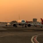 New Delhi, India: The Union Cabinet has approved a dedicated ₹5,000 crore emergency credit support window for Indian airlines under the Emergency Credit Line Guarantee Scheme (ECLGS) 5.0, as carriers grapple with mounting operational and financial pressure arising from the ongoing West Asia crisis. According to the official release issued by the Press Information Bureau (PIB) and the Ministry of Civil Aviation, Indian airlines have come under severe financial stress following a sharp surge in Aviation Turbine Fuel (ATF) prices, airspace restrictions and operational disruptions linked to the geopolitical situation in West Asia. The government said international operations have been particularly affected due to rerouted flight paths, longer flying times, lower aircraft utilisation and increased operating expenses, resulting in short-term liquidity mismatches for carriers. Under ECLGS 5.0, scheduled passenger airlines will be eligible for additional emergency credit support of up to 100% of their peak working capital utilisation during the fourth quarter of FY2025-26, subject to a cap of ₹1,500 crore per borrower. The loans sanctioned under the scheme will carry a seven-year tenure, including a two-year moratorium on principal repayment. The scheme will provide a 90% government guarantee cover on loans extended to airlines and non-MSME borrowers through the National Credit Guarantee Trustee Company Limited (NCGTC), while MSMEs will receive 100% guarantee coverage. The Cabinet said the move is intended to ensure continuity of operations, protect jobs, stabilise supply chains and maintain domestic economic activity amid rising geopolitical uncertainty and elevated crude oil prices. Eligible borrowers under the scheme include MSMEs, non-MSMEs with existing working capital limits and scheduled passenger airlines with outstanding credit facilities as of March 31, 2026, provided their accounts remain standard and non-performing assets are excluded. For MSMEs and other eligible businesses, additional borrowing will be capped at 20% of peak working capital utilisation during Q4 FY26, subject to a maximum of ₹100 crore. These loans will carry a five-year tenure with a one-year moratorium. The government has also waived guarantee fees under the scheme in a bid to accelerate credit flow and encourage banks and financial institutions to lend despite heightened risk conditions. The ECLGS 5.0 facility will remain open for sanctions until March 31, 2027. Information and Broadcasting Minister Ashwini Vaishnaw said the scheme was designed to provide immediate liquidity relief to sectors directly affected by the West Asia conflict and to prevent disruptions to industrial activity and employment. CAPA India described the measure as a major relief for the sector, noting that the government had already taken steps to secure ATF supplies and reduce operational costs before extending direct credit support. Market reaction remained positive following the announcement. Shares of InterGlobe Aviation, parent company of IndiGo, and SpiceJet gained after investors responded favourably to the liquidity support package. The latest ECLGS iteration marks the fifth version of the emergency credit programme originally introduced during the COVID-19 pandemic under the Atmanirbhar Bharat initiative to provide collateral-free, government-backed loans to stressed businesses. While industry bodies welcomed the move, some economists and market observers cautioned that extended moratoriums and large-scale guaranteed lending could create future repayment and credit discipline risks if geopolitical instability persists longer than expected. The announcement comes as India faces broader economic risks from volatile global oil prices, trade disruptions and reduced regional aviation efficiency linked to the escalating conflict in West Asia.