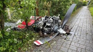 Limburgerhof, Germany: Two people were killed after a small aircraft crashed into a residential neighborhood in the German municipality of Limburgerhof in Rhineland-Palatinate on May 16, authorities and local media confirmed. The crash occurred at around 11:30 a.m. local time near Max-Planck-Straße on the outskirts of Limburgerhof, a town south of Mannheim with a population of about 11,600 residents. Police said the aircraft went down on a residential property, scattering debris across houses, garages, gardens, pathways and nearby streets over a wide area. According to police spokesperson Thorsten Mischler, both occupants of the aircraft died in the crash. Authorities later confirmed the victims were male. Initial police statements said there were no confirmed injuries among residents on the ground, although German outlet Welt reported that a 66-year-old woman was slightly injured after falling while trying to escape from falling debris. Witnesses described hearing a loud bang or explosion moments before the aircraft came down. Several eyewitnesses told investigators the plane appeared to explode in mid-air before crashing into the residential area. Reports also stated the aircraft may have clipped or grazed a house during its descent. Parts of the wreckage became lodged in fences while other debris landed in front of homes and across surrounding properties. The main section of the aircraft reportedly came to rest in the garden of a residential house. Police and emergency responders launched a major operation immediately after the crash. Authorities established a large security perimeter around the site while investigators documented debris locations and examined the wreckage. A police helicopter was deployed shortly after noon to capture aerial photographs of the accident scene as part of the investigation. Investigators said the aircraft had departed earlier in the day from Aachen in western Germany. However, officials stated that both the planned route and intended destination of the flight remain under investigation. The exact cause of the crash has not yet been determined. Authorities also appealed to residents and property owners in the area to report any additional debris or footage connected to the incident. Police requested that discovered wreckage pieces be left untouched until they could be officially documented and collected by investigators. A temporary support and information center for affected residents and witnesses was established at the Albert-Schweitzer-Haus in Limburgerhof.