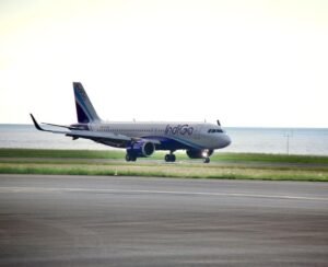 New Delhi, India: InterGlobe Aviation, the parent company of India’s largest airline, IndiGo, reported a consolidated net loss of ₹2,536.9 crore for the quarter ended March 31, 2026 (Q4 FY26), reversing from a net profit of ₹3,067.5 crore recorded during the corresponding quarter of the previous financial year. The sharp decline in profitability came amid significant foreign exchange losses, elevated fuel prices, operational disruptions, and one-time charges that weighed heavily on the carrier’s financial performance despite a marginal increase in revenue. According to the airline’s financial results, revenue from operations rose 1.3% year-on-year to ₹22,438 crore in the January-March 2026 quarter, compared with ₹22,152 crore in Q4 FY25. However, the increase in revenue was insufficient to offset mounting cost pressures. A major factor behind the quarterly loss was a foreign exchange loss of approximately ₹4,823 crore, driven by the depreciation of the Indian rupee against the US dollar. The impact was particularly significant for IndiGo as a large portion of its expenses including aircraft leases, maintenance costs and other aviation-related payments are dollar-denominated. The airline also faced rising aviation turbine fuel (ATF) costs during the quarter amid geopolitical tensions and higher crude oil prices. Fuel remains one of the largest expense components for airlines and contributed substantially to the pressure on margins. In addition, IndiGo reported a one-time charge of ₹250 crore during the quarter. The airline also continued to face operational challenges, including disruptions linked to airspace restrictions and capacity-related constraints that affected network efficiency. Despite the reported loss, the company stated that its underlying business performance remained profitable. Excluding the impact of foreign exchange fluctuations and exceptional items, IndiGo posted a net profit of approximately ₹1,921 crore during the quarter. For the full financial year ended March 31, 2026, IndiGo reported a consolidated net loss of around ₹2,394 crore. The company’s annual results were affected by foreign exchange losses of nearly ₹8,100 crore, disruption-related costs estimated at about ₹580 crore, and expenses of roughly ₹1,200 crore associated with the implementation of new labour regulations. At the operational level, IndiGo carried approximately 123.4 million passengers during FY26, representing a 4% increase compared with the previous year. Total income for the fiscal year rose 6.4% to ₹89,513 crore, reflecting continued demand growth in India’s aviation sector despite a challenging operating environment. The airline’s board also approved the partial prepayment of finance lease obligations owed to its wholly-owned subsidiary, InterGlobe Aviation Financial Services IFSC Private Limited. The prepayment, to be executed in one or more tranches, may total up to US$450 million and is intended to support future aircraft and aviation asset acquisitions. Management indicated that IndiGo is evaluating fuel hedging strategies after remaining largely unhedged during a period of heightened volatility in crude oil prices. The airline said such measures could help reduce exposure to future fuel price fluctuations. Looking ahead, IndiGo expects capacity growth to moderate in the near term. The airline has guided for capacity expansion of approximately 3-4% in the first quarter of FY27, significantly lower than the 16.4% growth recorded during the corresponding period a year earlier. Following the earnings announcement, market participants indicated that IndiGo shares would remain in focus as investors assess the impact of currency movements, fuel costs, regulatory developments and operational performance on the airline’s future profitability.