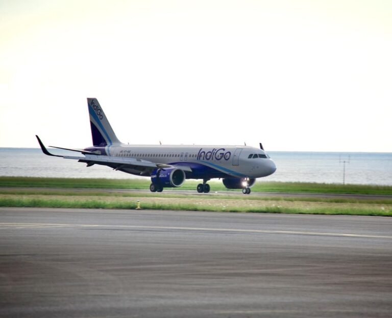 New Delhi, India: InterGlobe Aviation, the parent company of India’s largest airline, IndiGo, reported a consolidated net loss of ₹2,536.9 crore for the quarter ended March 31, 2026 (Q4 FY26), reversing from a net profit of ₹3,067.5 crore recorded during the corresponding quarter of the previous financial year. The sharp decline in profitability came amid significant foreign exchange losses, elevated fuel prices, operational disruptions, and one-time charges that weighed heavily on the carrier’s financial performance despite a marginal increase in revenue. According to the airline’s financial results, revenue from operations rose 1.3% year-on-year to ₹22,438 crore in the January-March 2026 quarter, compared with ₹22,152 crore in Q4 FY25. However, the increase in revenue was insufficient to offset mounting cost pressures. A major factor behind the quarterly loss was a foreign exchange loss of approximately ₹4,823 crore, driven by the depreciation of the Indian rupee against the US dollar. The impact was particularly significant for IndiGo as a large portion of its expenses including aircraft leases, maintenance costs and other aviation-related payments are dollar-denominated. The airline also faced rising aviation turbine fuel (ATF) costs during the quarter amid geopolitical tensions and higher crude oil prices. Fuel remains one of the largest expense components for airlines and contributed substantially to the pressure on margins. In addition, IndiGo reported a one-time charge of ₹250 crore during the quarter. The airline also continued to face operational challenges, including disruptions linked to airspace restrictions and capacity-related constraints that affected network efficiency. Despite the reported loss, the company stated that its underlying business performance remained profitable. Excluding the impact of foreign exchange fluctuations and exceptional items, IndiGo posted a net profit of approximately ₹1,921 crore during the quarter. For the full financial year ended March 31, 2026, IndiGo reported a consolidated net loss of around ₹2,394 crore. The company’s annual results were affected by foreign exchange losses of nearly ₹8,100 crore, disruption-related costs estimated at about ₹580 crore, and expenses of roughly ₹1,200 crore associated with the implementation of new labour regulations. At the operational level, IndiGo carried approximately 123.4 million passengers during FY26, representing a 4% increase compared with the previous year. Total income for the fiscal year rose 6.4% to ₹89,513 crore, reflecting continued demand growth in India’s aviation sector despite a challenging operating environment. The airline’s board also approved the partial prepayment of finance lease obligations owed to its wholly-owned subsidiary, InterGlobe Aviation Financial Services IFSC Private Limited. The prepayment, to be executed in one or more tranches, may total up to US$450 million and is intended to support future aircraft and aviation asset acquisitions. Management indicated that IndiGo is evaluating fuel hedging strategies after remaining largely unhedged during a period of heightened volatility in crude oil prices. The airline said such measures could help reduce exposure to future fuel price fluctuations. Looking ahead, IndiGo expects capacity growth to moderate in the near term. The airline has guided for capacity expansion of approximately 3-4% in the first quarter of FY27, significantly lower than the 16.4% growth recorded during the corresponding period a year earlier. Following the earnings announcement, market participants indicated that IndiGo shares would remain in focus as investors assess the impact of currency movements, fuel costs, regulatory developments and operational performance on the airline’s future profitability.