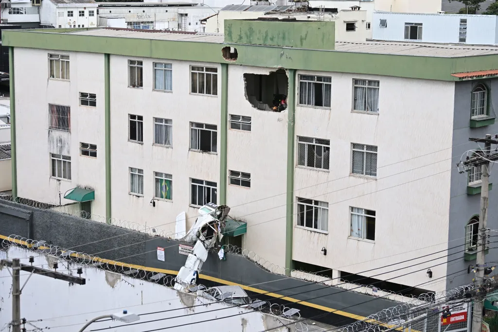 Belo Horizonte, Brazil: A small twin-engine aircraft crashed into a residential building in the Silveira neighbourhood of Belo Horizonte on Monday, killing three of the five people onboard and injuring two others, according to Brazilian authorities. The aircraft, identified as an Embraer EMB-721C, departed from Pampulha Airport at approximately 12:16 p.m. local time, bound for São Paulo. Within minutes of takeoff, the aircraft began experiencing difficulties and remained airborne for only a short duration before losing altitude. It ultimately crashed around 12:25 p.m. into a three-storey residential building, striking a stairwell area between floors, which helped prevent casualties among residents. Authorities confirmed that three occupants died in the crash. The victims include pilot Wellington Oliveira and passenger Fernando Moreira Souto, who was the son of the mayor of Jequitinhonha. Souto was initially rescued in critical condition but later succumbed to his injuries in hospital. The co-pilot also died, though their identity has not been officially released in primary reports. Two other passengers survived the crash and were taken to hospital, where they are reported to be in stable condition. Eyewitness accounts and initial footage indicate that the aircraft appeared to be circling and descending abnormally before impact, suggesting a possible loss of power or control shortly after departure. Despite the direct collision with the building, no residents on the ground were injured, and structural damage was limited, avoiding a potentially larger disaster. Emergency responders, including firefighters, medical teams and civil defence personnel, reached the crash site within minutes. Residents of the building were evacuated as a precaution while authorities secured the area and assisted survivors. The cause of the crash remains under investigation. Brazil’s Aeronautical Accidents Investigation and Prevention Center (CENIPA), along with regional unit SERIPA III and the Civil Police of Minas Gerais, have launched a formal probe. Investigators are examining possible mechanical issues, operational factors and the aircraft’s condition. In response to the incident, officials in Jequitinhonha declared three days of mourning following the death of Fernando Moreira Souto. Authorities have not yet released a final determination on what led to the crash, and investigations are ongoing.