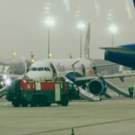 Bangalore; India: A major aviation scare unfolded at Kempegowda International Airport on Tuesday evening after smoke was detected inside an IndiGo Airbus A321neo operating a Bengaluru-Chennai flight, forcing the emergency evacuation of more than 230 passengers and crew members just before takeoff. According to the Directorate General of Civil Aviation (DGCA) and airline officials, the incident involved IndiGo flight 6E 6017, which had begun taxiing towards the runway when smoke was observed inside both the cabin and cockpit, triggering an immediate emergency response. The aircraft had completed pushback and was taxiing for departure to Chennai when smoke was reported onboard. Following the detection, the flight crew immediately halted operations and ordered an emergency evacuation as a precautionary measure. All passengers were evacuated using the aircraft’s emergency escape slides on the taxiway, with airport fire and emergency response teams rushing to assist. The evacuation was completed before the aircraft could line up for takeoff. During the emergency evacuation, two passengers sustained minor injuries, according to DGCA and multiple media reports. They were provided immediate medical attention at the terminal and were reported to be in stable condition. Despite the panic, authorities confirmed that all passengers and crew were safely evacuated. IndiGo confirmed the incident and stated that safety procedures were followed immediately after smoke was detected. “On 26 May 2026, while IndiGo flight 6E 6017 from Bengaluru to Chennai was taxiing toward the runway for departure, smoke was noticed in the aircraft. In the interest of safety, an immediate evacuation was carried out, and all relevant authorities were informed. All customers and crew are safe and have been moved to the terminal, where they are being attended to by our teams to ensure their well-being,” the airline said in its official statement. The airline also arranged an alternate aircraft to operate the Bengaluru-Chennai service and provided assistance to affected passengers. The DGCA confirmed that the aircraft, an Airbus A321neo (VT-IME), has been grounded for inspection and rectification. According to the regulator, smoke was reported shortly after pushback when the aircraft began taxiing, with observations indicating smoke presence in both the cockpit and cabin. A detailed investigation has been initiated to determine the root cause. Authorities are examining possible technical issues, including: Electrical system malfunction Air-conditioning or auxiliary system failure Potential wiring or equipment overheating Passengers described a sudden and alarming situation as smoke filled parts of the aircraft during taxiing. One passenger saidI that smoke appeared shortly after the flight began moving, causing immediate panic among those onboard. Another passenger described “dense smoke” and a strong smell inside the cabin, adding that elderly passengers and children faced difficulties during the evacuation process. Eyewitness accounts also noted that passengers rushed toward exits as crew members guided them through emergency procedures. The exact cause of the smoke remains under investigation, with DGCA expected to release preliminary findings after a detailed technical inspection of the aircraft systems.
