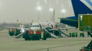 Bangalore; India: A major aviation scare unfolded at Kempegowda International Airport on Tuesday evening after smoke was detected inside an IndiGo Airbus A321neo operating a Bengaluru-Chennai flight, forcing the emergency evacuation of more than 230 passengers and crew members just before takeoff. According to the Directorate General of Civil Aviation (DGCA) and airline officials, the incident involved IndiGo flight 6E 6017, which had begun taxiing towards the runway when smoke was observed inside both the cabin and cockpit, triggering an immediate emergency response. The aircraft had completed pushback and was taxiing for departure to Chennai when smoke was reported onboard. Following the detection, the flight crew immediately halted operations and ordered an emergency evacuation as a precautionary measure. All passengers were evacuated using the aircraft’s emergency escape slides on the taxiway, with airport fire and emergency response teams rushing to assist. The evacuation was completed before the aircraft could line up for takeoff. During the emergency evacuation, two passengers sustained minor injuries, according to DGCA and multiple media reports. They were provided immediate medical attention at the terminal and were reported to be in stable condition. Despite the panic, authorities confirmed that all passengers and crew were safely evacuated. IndiGo confirmed the incident and stated that safety procedures were followed immediately after smoke was detected. “On 26 May 2026, while IndiGo flight 6E 6017 from Bengaluru to Chennai was taxiing toward the runway for departure, smoke was noticed in the aircraft. In the interest of safety, an immediate evacuation was carried out, and all relevant authorities were informed. All customers and crew are safe and have been moved to the terminal, where they are being attended to by our teams to ensure their well-being,” the airline said in its official statement. The airline also arranged an alternate aircraft to operate the Bengaluru-Chennai service and provided assistance to affected passengers. The DGCA confirmed that the aircraft, an Airbus A321neo (VT-IME), has been grounded for inspection and rectification. According to the regulator, smoke was reported shortly after pushback when the aircraft began taxiing, with observations indicating smoke presence in both the cockpit and cabin. A detailed investigation has been initiated to determine the root cause. Authorities are examining possible technical issues, including: Electrical system malfunction Air-conditioning or auxiliary system failure Potential wiring or equipment overheating Passengers described a sudden and alarming situation as smoke filled parts of the aircraft during taxiing. One passenger saidI that smoke appeared shortly after the flight began moving, causing immediate panic among those onboard. Another passenger described “dense smoke” and a strong smell inside the cabin, adding that elderly passengers and children faced difficulties during the evacuation process. Eyewitness accounts also noted that passengers rushed toward exits as crew members guided them through emergency procedures. The exact cause of the smoke remains under investigation, with DGCA expected to release preliminary findings after a detailed technical inspection of the aircraft systems.