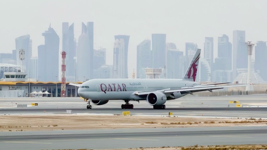 Doha, Qatar: Qatar Airways posted a net profit of QAR 7.08 billion ($1.94 billion) for the 2025/26 financial year, overcoming one of the most challenging operating environments faced by Gulf carriers in recent years as regional conflict disrupted air travel across the Middle East. The airline group’s annual earnings declined more than 7% compared with the previous fiscal year, when it had reported a record QAR 7.8 billion ($2.1 billion) profit. However, the latest results still rank among the strongest in the carrier’s history, reflecting resilient passenger demand, strong cargo performance, and operational stability despite widespread geopolitical disruption. The state-owned airline said the financial year ending March 31, 2026, was heavily impacted during its final quarter by escalating regional tensions linked to the Iran conflict, which triggered temporary airspace closures, flight diversions, schedule disruptions, and higher operating costs across the Gulf aviation sector. The crisis forced airlines throughout the region to cancel thousands of flights and reroute aircraft, creating the most significant operational disruption for Middle Eastern carriers since the COVID-19 pandemic. Despite those challenges, Qatar Airways carried more than 41.8 million passengers during the fiscal year through its Doha hub at Hamad International Airport. Passenger traffic was slightly lower than the 43.1 million travelers recorded a year earlier, reflecting the impact of regional instability during the final months of the reporting period. Cargo operations remained a major contributor to the airline’s financial performance. Qatar Airways Cargo transported more than 1.43 million tonnes of chargeable freight during the year and maintained a 12% share of the global air cargo market, reinforcing its position as one of the world’s largest international freight carriers. Chief Executive Officer Hamad Al-Khater described the financial year as a period that tested both the airline’s commercial strength and operational resilience. He said the company’s performance demonstrated the strength of its balance sheet, partnerships, and workforce despite operating under “genuine pressure” during the regional crisis. The airline said approximately 57,800 employees across more than 90 countries supported operations throughout the crisis period, particularly during the final weeks of the financial year when regional airspace disruptions intensified. Operationally, Qatar Airways maintained an on-time performance rate of 86%, placing it among the world’s top five most punctual airlines, according to Cirium rankings. The carrier also received the Cirium Platinum Award for Operational Excellence during the reporting period. The airline continued expanding its long-haul connectivity and technology offerings during the fiscal year. Qatar Airways said it now operates the world’s largest Starlink-equipped widebody fleet, with onboard high-speed internet services available on Boeing 777, Airbus A350, and Boeing 787-8 aircraft. In one of the aviation industry’s biggest fleet commitments, the airline group also signed agreements with Boeing and GE Aerospace covering up to 210 aircraft and 400 engines. The agreements are among the largest widebody aircraft and engine deals in commercial aviation history. The airline is now focused on rebuilding capacity and restoring network connectivity following the regional disruptions. Executives said Qatar Airways plans to expand its network to more than 160 destinations by summer 2026 as Gulf carriers gradually restore schedules impacted by the conflict.