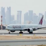 Doha, Qatar: Qatar Airways posted a net profit of QAR 7.08 billion ($1.94 billion) for the 2025/26 financial year, overcoming one of the most challenging operating environments faced by Gulf carriers in recent years as regional conflict disrupted air travel across the Middle East. The airline group’s annual earnings declined more than 7% compared with the previous fiscal year, when it had reported a record QAR 7.8 billion ($2.1 billion) profit. However, the latest results still rank among the strongest in the carrier’s history, reflecting resilient passenger demand, strong cargo performance, and operational stability despite widespread geopolitical disruption. The state-owned airline said the financial year ending March 31, 2026, was heavily impacted during its final quarter by escalating regional tensions linked to the Iran conflict, which triggered temporary airspace closures, flight diversions, schedule disruptions, and higher operating costs across the Gulf aviation sector. The crisis forced airlines throughout the region to cancel thousands of flights and reroute aircraft, creating the most significant operational disruption for Middle Eastern carriers since the COVID-19 pandemic. Despite those challenges, Qatar Airways carried more than 41.8 million passengers during the fiscal year through its Doha hub at Hamad International Airport. Passenger traffic was slightly lower than the 43.1 million travelers recorded a year earlier, reflecting the impact of regional instability during the final months of the reporting period. Cargo operations remained a major contributor to the airline’s financial performance. Qatar Airways Cargo transported more than 1.43 million tonnes of chargeable freight during the year and maintained a 12% share of the global air cargo market, reinforcing its position as one of the world’s largest international freight carriers. Chief Executive Officer Hamad Al-Khater described the financial year as a period that tested both the airline’s commercial strength and operational resilience. He said the company’s performance demonstrated the strength of its balance sheet, partnerships, and workforce despite operating under “genuine pressure” during the regional crisis. The airline said approximately 57,800 employees across more than 90 countries supported operations throughout the crisis period, particularly during the final weeks of the financial year when regional airspace disruptions intensified. Operationally, Qatar Airways maintained an on-time performance rate of 86%, placing it among the world’s top five most punctual airlines, according to Cirium rankings. The carrier also received the Cirium Platinum Award for Operational Excellence during the reporting period. The airline continued expanding its long-haul connectivity and technology offerings during the fiscal year. Qatar Airways said it now operates the world’s largest Starlink-equipped widebody fleet, with onboard high-speed internet services available on Boeing 777, Airbus A350, and Boeing 787-8 aircraft. In one of the aviation industry’s biggest fleet commitments, the airline group also signed agreements with Boeing and GE Aerospace covering up to 210 aircraft and 400 engines. The agreements are among the largest widebody aircraft and engine deals in commercial aviation history. The airline is now focused on rebuilding capacity and restoring network connectivity following the regional disruptions. Executives said Qatar Airways plans to expand its network to more than 160 destinations by summer 2026 as Gulf carriers gradually restore schedules impacted by the conflict.