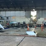 Adelaide, Australia: A fractured nose landing gear actuator has emerged as a significant focus of the Australian Transport Safety Bureau's (ATSB) investigation into the fatal Diamond DA42 training aircraft crash at Parafield Airport, South Australia, which killed two pilots and injured nine people on the ground. The findings were released on June 23, 2026, in a preliminary report into the April 29 accident involving Diamond DA42 Twin Star aircraft VH-YQP, operated by Flight Training Adelaide (FTA). The ATSB emphasized that the report is preliminary and does not determine the final cause of the accident. The aircraft departed Runway 03 Left at Parafield Airport at approximately 2:08 p.m. local time while conducting a training flight involving simulated engine-failure exercises. On board were a 24-year-old pilot under instruction and 29-year-old flight instructor Robert Hoyle. According to investigators, the aircraft initially climbed normally before CCTV footage showed it deviating left of the runway centerline. The aircraft was briefly realigned before veering left again. During the climb, the main landing gear retracted, but the nose landing gear remained extended. Approximately 27 seconds after takeoff, at about 115 feet above ground level, the instructor transmitted an "engine failure" radio call. No further transmissions were received. The aircraft continued climbing and reached a maximum recorded altitude of approximately 161 feet above ground level before entering a loss-of-control sequence. Investigators said the aircraft subsequently pitched up, rolled left, and descended steeply before colliding with a Flight Training Adelaide classroom and hangar complex. The impact triggered a major fire that destroyed the aircraft and damaged several others on the ground. Both occupants were fatally injured. Nine people on the ground sustained injuries, including several who required hospitalization. A key discovery during the wreckage examination was a fractured nose landing gear actuator rod end. ATSB investigators determined that the component had separated from the landing gear assembly. Preliminary examination found evidence of progressive fatigue cracking before the final fracture occurred. "The circumstances of the accident were consistent with pre-accident fracture of the rod end, resulting in the nose landing gear being observed down while the main gear was retracted," the ATSB stated. Investigators are examining whether the detached actuator may have interfered with the aircraft's steering and rudder control systems. The ATSB noted that Diamond Aircraft Industries had previously identified similar failures and issued mandatory service bulletins in 2013 and 2019 following other nose landing gear actuator fractures in DA42 aircraft. One previously documented occurrence described by the manufacturer involved a fractured actuator moving out of position and interacting with rudder controls, causing an uncommanded left rudder deflection. In that case, the pilot regained control after extending the landing gear. ATSB Chief Commissioner Angus Mitchell highlighted the significance of that earlier event. "In the DA42, re-extending the landing gear after take-off may not be a usual action considered by pilots, but as noted in the manufacturer's service bulletin explanation of a previous incident, this action allowed the pilot to regain aircraft control," Mitchell said. As a result of the findings, the ATSB has issued Safety Advisory Notice AO-2026-074-SAN-001 to alert DA42 operators to the increased risk of uncommanded left rudder deflection following a nose landing gear actuator fracture. The investigation is also focusing on the aircraft's engines. Examination of the wreckage found that the left engine showed no indications of producing power at impact, while the left propeller was found in the feathered position. Investigators have not yet determined whether the engine issue was genuine, simulated as part of the training exercise, or developed during the flight. The ATSB stated that multiple scenarios remain under consideration. The preliminary report also highlighted that Flight Training Adelaide's procedures required simulated engine-failure exercises after takeoff to be conducted no lower than 400 feet above ground level. The accident aircraft never exceeded 161 feet. To date, investigators have examined the wreckage, reviewed maintenance and operational records, obtained air traffic control data, analyzed ADS-B flight tracking information, collected CCTV footage, and interviewed witnesses. Further work will include detailed metallurgical examination of the fractured actuator component, engine analysis, review of recorded data, maintenance documentation, operational procedures, survivability considerations, and comparisons with related occurrences. The ATSB stressed that its role is to improve transport safety rather than assign blame. "The ATSB is also considering other scenarios to explain the accident sequence," the bureau said. The investigation remains active, and a final report is expected following completion of the technical analysis. The ATSB said any critical safety issues identified before then will be communicated immediately to relevant parties so corrective action can be taken.