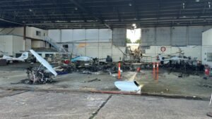 Adelaide, Australia: A fractured nose landing gear actuator has emerged as a significant focus of the Australian Transport Safety Bureau's (ATSB) investigation into the fatal Diamond DA42 training aircraft crash at Parafield Airport, South Australia, which killed two pilots and injured nine people on the ground. The findings were released on June 23, 2026, in a preliminary report into the April 29 accident involving Diamond DA42 Twin Star aircraft VH-YQP, operated by Flight Training Adelaide (FTA). The ATSB emphasized that the report is preliminary and does not determine the final cause of the accident. The aircraft departed Runway 03 Left at Parafield Airport at approximately 2:08 p.m. local time while conducting a training flight involving simulated engine-failure exercises. On board were a 24-year-old pilot under instruction and 29-year-old flight instructor Robert Hoyle. According to investigators, the aircraft initially climbed normally before CCTV footage showed it deviating left of the runway centerline. The aircraft was briefly realigned before veering left again. During the climb, the main landing gear retracted, but the nose landing gear remained extended. Approximately 27 seconds after takeoff, at about 115 feet above ground level, the instructor transmitted an "engine failure" radio call. No further transmissions were received. The aircraft continued climbing and reached a maximum recorded altitude of approximately 161 feet above ground level before entering a loss-of-control sequence. Investigators said the aircraft subsequently pitched up, rolled left, and descended steeply before colliding with a Flight Training Adelaide classroom and hangar complex. The impact triggered a major fire that destroyed the aircraft and damaged several others on the ground. Both occupants were fatally injured. Nine people on the ground sustained injuries, including several who required hospitalization. A key discovery during the wreckage examination was a fractured nose landing gear actuator rod end. ATSB investigators determined that the component had separated from the landing gear assembly. Preliminary examination found evidence of progressive fatigue cracking before the final fracture occurred. "The circumstances of the accident were consistent with pre-accident fracture of the rod end, resulting in the nose landing gear being observed down while the main gear was retracted," the ATSB stated. Investigators are examining whether the detached actuator may have interfered with the aircraft's steering and rudder control systems. The ATSB noted that Diamond Aircraft Industries had previously identified similar failures and issued mandatory service bulletins in 2013 and 2019 following other nose landing gear actuator fractures in DA42 aircraft. One previously documented occurrence described by the manufacturer involved a fractured actuator moving out of position and interacting with rudder controls, causing an uncommanded left rudder deflection. In that case, the pilot regained control after extending the landing gear. ATSB Chief Commissioner Angus Mitchell highlighted the significance of that earlier event. "In the DA42, re-extending the landing gear after take-off may not be a usual action considered by pilots, but as noted in the manufacturer's service bulletin explanation of a previous incident, this action allowed the pilot to regain aircraft control," Mitchell said. As a result of the findings, the ATSB has issued Safety Advisory Notice AO-2026-074-SAN-001 to alert DA42 operators to the increased risk of uncommanded left rudder deflection following a nose landing gear actuator fracture. The investigation is also focusing on the aircraft's engines. Examination of the wreckage found that the left engine showed no indications of producing power at impact, while the left propeller was found in the feathered position. Investigators have not yet determined whether the engine issue was genuine, simulated as part of the training exercise, or developed during the flight. The ATSB stated that multiple scenarios remain under consideration. The preliminary report also highlighted that Flight Training Adelaide's procedures required simulated engine-failure exercises after takeoff to be conducted no lower than 400 feet above ground level. The accident aircraft never exceeded 161 feet. To date, investigators have examined the wreckage, reviewed maintenance and operational records, obtained air traffic control data, analyzed ADS-B flight tracking information, collected CCTV footage, and interviewed witnesses. Further work will include detailed metallurgical examination of the fractured actuator component, engine analysis, review of recorded data, maintenance documentation, operational procedures, survivability considerations, and comparisons with related occurrences. The ATSB stressed that its role is to improve transport safety rather than assign blame. "The ATSB is also considering other scenarios to explain the accident sequence," the bureau said. The investigation remains active, and a final report is expected following completion of the technical analysis. The ATSB said any critical safety issues identified before then will be communicated immediately to relevant parties so corrective action can be taken.