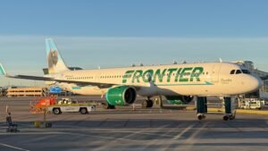 Miami, United States: A Frontier Airlines flight bound for Chicago was forced to divert to Miami after a passenger allegedly attempted to open an emergency exit door, tried to access the cockpit area, assaulted an off-duty flight attendant, and repeatedly disrupted the flight, according to law enforcement authorities and court documents. The incident occurred aboard Frontier Airlines Flight 3345, which departed San Juan, Puerto Rico, and was en route to Chicago O'Hare International Airport on May 31. Authorities identified the passenger as Juan Gabriel Reyes, 51, of Pahokee, Florida. According to an arrest report cited by Miami-Dade Sheriff's Office investigators, Reyes began causing disturbances approximately 45 minutes after takeoff. Authorities said he attempted to open one of the aircraft's emergency exit doors while the Airbus was in flight, reportedly telling crew members that he wanted to leave the aircraft. Flight attendants intervened and instructed Reyes to return to his seat. However, investigators said he ignored repeated crew commands and continued behaving erratically. The arrest affidavit states that Reyes then moved toward the front of the aircraft and allegedly attempted to gain access to the cockpit area by aggressively pushing against the flight deck door with his shoulder. After crew members escorted him away from the cockpit area, Reyes requested permission to use the lavatory. Authorities said he was allowed to do so but allegedly attempted to urinate on the restroom floor, creating another disturbance onboard. Due to his continued disruptive behavior, flight attendants relocated Reyes to another seat. An off-duty Frontier Airlines flight attendant volunteered to sit nearby and assist in monitoring him during the remainder of the flight. According to investigators, the off-duty employee later left his seat and placed his bag nearby before heading toward the lavatory. Another passenger reportedly alerted him that Reyes was attempting to take the bag. When the employee confronted Reyes, authorities allege that Reyes grabbed him and placed him in a chokehold, prompting an immediate response from passengers and crew members. Video recorded by passengers and widely circulated on social media showed multiple travelers and flight attendants struggling to restrain Reyes as chaos unfolded inside the cabin. Among those who intervened was Josh Longood, a former professional mixed martial arts fighter and Brazilian Jiu-Jitsu black belt. Longood assisted crew members and passengers in subduing Reyes and securing him using flex cuffs, zip ties, and seatbelt extenders. Court documents indicate that Reyes managed to break free from restraints multiple times, requiring passengers and crew to continue physically holding him down until the aircraft landed. The Federal Aviation Administration confirmed that the flight crew reported a passenger disturbance and diverted the aircraft to Miami International Airport as a precaution. Flight 3345 landed safely at approximately 11:55 a.m. local time in Miami, where Miami-Dade Sheriff's Office deputies boarded the aircraft and removed Reyes from the plane. Authorities initially charged Reyes with battery in connection with the alleged assault on the off-duty flight attendant. He was booked into the Miami-Dade jail and held on a reported $20,000 bond. According to court records cited by the Miami Herald, Reyes was later turned over to FBI agents for potential federal prosecution. Investigators indicated he could face additional federal charges, including interference with a flight crew and assault within maritime and territorial jurisdiction. No injuries requiring hospitalization were reported among passengers or crew. Frontier Airlines confirmed that law enforcement officers met the aircraft upon arrival in Miami and removed the disruptive passenger. Following the incident, the flight later resumed its journey to Chicago O'Hare International Airport. The FAA said it is aware of the incident and the investigation remains ongoing.