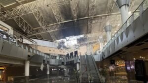 Kuwait International Airport suffered severe damage after an Iranian drone strike hit Terminal 1 on June 3, 2026, killing one person and injuring dozens in one of the most serious attacks on civilian aviation infrastructure in the Gulf since the outbreak of the regional conflict earlier this year. According to Kuwaiti authorities, the attack occurred during a broader wave of Iranian missile and drone launches targeting Kuwait and other Gulf states. The strike damaged large sections of Terminal 1, forcing flight diversions, temporary suspension of airport operations and emergency response measures across the airport complex. Kuwait's Directorate General of Civil Aviation (DGCA) later released CCTV footage showing the moment of impact. The video released by officials appears to show a delta-wing drone striking the terminal before a large explosion erupts, sending debris, smoke and flames through parts of the building. Aviation officials said the footage was released after emergency teams secured the affected areas and initial damage assessments were completed. Authorities reported that one person was killed and at least 63 others were injured. Emergency responders treated victims at the scene while firefighters worked to contain fires sparked by the attack. The DGCA said Terminal 1 sustained extensive structural damage, including collapsed ceiling sections, shattered glass and damage to airport facilities. Flight operations were temporarily disrupted, with several aircraft diverted to alternate airports. Kuwait Airways suspended scheduled services before later resuming limited operations from Terminal 4 following safety inspections and operational assessments. The strike came hours after a sharp escalation between Iran and the United States. U.S. forces reportedly conducted military action against Iranian targets, including facilities on Qeshm Island and maritime assets linked to Tehran. Iranian officials subsequently launched retaliatory missile and drone attacks against multiple locations across the Gulf region. U.S. Central Command stated that several Iranian missiles aimed at Kuwait and Bahrain either malfunctioned, fell short or were intercepted. Military officials also reported that additional drones targeting U.S. forces in Kuwait failed to reach their intended objectives. Kuwaiti officials condemned the attack, describing it as a violation of national sovereignty and an assault on civilian infrastructure. The country's Foreign Ministry said the strikes targeted civilian facilities, including the international airport, and warned that such actions threatened regional stability and aviation safety. The attack represents the latest incident involving Kuwait International Airport during the wider Iran-related conflict. Earlier drone attacks during the spring damaged airport infrastructure, fuel facilities and radar systems, prompting prolonged disruptions and temporary airport closures. Although operations gradually resumed following an April ceasefire, the June 3 strike renewed concerns over the vulnerability of civilian aviation facilities in the region. The released footage appears to show a drone resembling Iran's Shahed-family unmanned aircraft, a design that has been widely used in regional conflicts. While authorities have not publicly confirmed the exact model involved, aviation and defense analysts cited by international media noted similarities in the aircraft's shape and flight profile. The incident also triggered immediate travel disruptions. Airlines reviewed operations to Kuwait, while India's IndiGo issued a travel advisory and suspended flights to and from the country amid the deteriorating security situation. Investigations into the attack, including the assessment of damage, casualty figures and operational impact, remain ongoing. Kuwaiti authorities continue to evaluate the airport's infrastructure while implementing additional security measures to protect aviation operations.