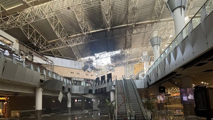 Kuwait International Airport suffered severe damage after an Iranian drone strike hit Terminal 1 on June 3, 2026, killing one person and injuring dozens in one of the most serious attacks on civilian aviation infrastructure in the Gulf since the outbreak of the regional conflict earlier this year. According to Kuwaiti authorities, the attack occurred during a broader wave of Iranian missile and drone launches targeting Kuwait and other Gulf states. The strike damaged large sections of Terminal 1, forcing flight diversions, temporary suspension of airport operations and emergency response measures across the airport complex. Kuwait's Directorate General of Civil Aviation (DGCA) later released CCTV footage showing the moment of impact. The video released by officials appears to show a delta-wing drone striking the terminal before a large explosion erupts, sending debris, smoke and flames through parts of the building. Aviation officials said the footage was released after emergency teams secured the affected areas and initial damage assessments were completed. Authorities reported that one person was killed and at least 63 others were injured. Emergency responders treated victims at the scene while firefighters worked to contain fires sparked by the attack. The DGCA said Terminal 1 sustained extensive structural damage, including collapsed ceiling sections, shattered glass and damage to airport facilities. Flight operations were temporarily disrupted, with several aircraft diverted to alternate airports. Kuwait Airways suspended scheduled services before later resuming limited operations from Terminal 4 following safety inspections and operational assessments. The strike came hours after a sharp escalation between Iran and the United States. U.S. forces reportedly conducted military action against Iranian targets, including facilities on Qeshm Island and maritime assets linked to Tehran. Iranian officials subsequently launched retaliatory missile and drone attacks against multiple locations across the Gulf region. U.S. Central Command stated that several Iranian missiles aimed at Kuwait and Bahrain either malfunctioned, fell short or were intercepted. Military officials also reported that additional drones targeting U.S. forces in Kuwait failed to reach their intended objectives. Kuwaiti officials condemned the attack, describing it as a violation of national sovereignty and an assault on civilian infrastructure. The country's Foreign Ministry said the strikes targeted civilian facilities, including the international airport, and warned that such actions threatened regional stability and aviation safety. The attack represents the latest incident involving Kuwait International Airport during the wider Iran-related conflict. Earlier drone attacks during the spring damaged airport infrastructure, fuel facilities and radar systems, prompting prolonged disruptions and temporary airport closures. Although operations gradually resumed following an April ceasefire, the June 3 strike renewed concerns over the vulnerability of civilian aviation facilities in the region. The released footage appears to show a drone resembling Iran's Shahed-family unmanned aircraft, a design that has been widely used in regional conflicts. While authorities have not publicly confirmed the exact model involved, aviation and defense analysts cited by international media noted similarities in the aircraft's shape and flight profile. The incident also triggered immediate travel disruptions. Airlines reviewed operations to Kuwait, while India's IndiGo issued a travel advisory and suspended flights to and from the country amid the deteriorating security situation. Investigations into the attack, including the assessment of damage, casualty figures and operational impact, remain ongoing. Kuwaiti authorities continue to evaluate the airport's infrastructure while implementing additional security measures to protect aviation operations.