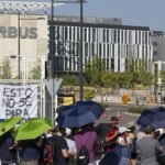 Madrid, Spain: Thousands of Airbus workers in Spain remain on an indefinite strike on August 27, 2026, after rejecting the company's latest proposal on pay and working conditions. The industrial action began on August 25, 2026 after employees represented by UGT, CGT and ÚTIL voted overwhelmingly to continue the stoppage. A fresh mediation meeting between Airbus and the unions was scheduled at Spain's Interconfederal Mediation and Arbitration Service (SIMA-FSP) on Thursday, 27, 2026 as both sides seek to break the deadlock. The dispute involves Airbus facilities in Getafe and Illescas, as well as the San Pablo and Tablada plants in Seville and the Albacete site. Airbus has more than 14,000 employees across Spain. The Cádiz workforce has not yet held its final vote, with its assembly postponed to September 1, but it is following the majority decision of the other centres for now. The unions are demanding improvements in wages and the restoration of employment conditions they say were changed unilaterally. Their concerns include recovering lost purchasing power, teleworking, holidays, working-time flexibility, transport and cafeteria arrangements, as well as issues surrounding sick-leave payments and employment guarantees. UGT said the central objectives behind the strike are enforcement of existing legal, contractual and collective-agreement obligations, reversal of unilateral company decisions and a genuine collective bargaining process. Airbus has made several concessions during the mediation process. The company offered a salary increase linked to the consumer price index (CPI), together with an additional component aimed at recovering lost purchasing power. It also agreed to restore the previous teleworking arrangements and individual agreements. Airbus confirmed that it had withdrawn its appeal before Spain's Supreme Court concerning sick-leave payments and said amounts previously deducted from employees would be returned. However, the unions considered the offer insufficient because several important issues remained unresolved or lacked firm financial and implementation details. UGT said the company still needed to provide clearer commitments on matters including holidays, working-time flexibility, transport, cafeteria arrangements, job classifications and conditions at Cádiz. The union said negotiations would continue until the workforce's objectives were addressed. Airbus has publicly expressed disappointment over the decision to proceed with the indefinite strike and warned that reaching an agreement quickly is critical. The company said it was assessing the additional impact of the stoppage on its production obligations, customer agreements, institutional commitments and reputation. Airbus has also maintained that it wants to continue negotiations and convert its latest proposals into a mutually acceptable agreement. UGT General Secretary at Airbus Edmundo Otero told Reuters that he saw “elements that give us reason for cautious optimism” over issues including inflation-linked pay, but said greater clarity was still needed. Airbus, meanwhile, said it regretted the decision to continue the indefinite strike and warned that reaching an agreement quickly was critical for the company, its customers and its operations in Spain. An Airbus spokesperson also said the company’s objective remained increased on-site presence, but acknowledged that implementing changes required “listening to our people.” The current dispute follows a previous round of industrial action in July, when Airbus workers in Spain staged strikes from July 1, 2026 through late July, 2026. The earlier protests were linked to pay, teleworking and wider concerns over employment conditions. The conflict intensified after workers rejected an earlier agreement, prompting Airbus and the unions to turn to mediation through Spain’s Interconfederal Mediation and Arbitration Service (SIMA). The teleworking dispute has also become a wider issue within Airbus. Airbus had scaled back its planned return-to-office policy following protests and strikes, particularly in Spain. The company had sought to increase office attendance but subsequently retained an average of two remote-working days per week, allowing managers greater flexibility in implementing hybrid arrangements. The July action involved around 40% of Airbus' 14,000-strong Spanish workforce, while production had not been affected at that stage. The renewed strike comes at a difficult time for Airbus' production plans. The company delivered 67 commercial aircraft in July and needs to average roughly 90 deliveries per month through the remainder of 2026 to meet its annual target of 870 aircraft. Any prolonged disruption at its Spanish facilities could therefore add pressure to an already demanding production schedule. As of August 27, 2026, the strike remains ongoing and indefinite. There is no announced end date. The immediate focus is on the latest SIMA negotiations, with Airbus and the unions attempting to narrow their differences while workers continue the industrial action.