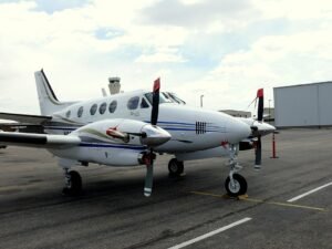 New Mexico, United States: The U.S. National Transportation Safety Board (NTSB) has revealed that a U.S. military GPS jamming exercise was underway when a Beechcraft C90 King Air air ambulance crashed into mountainous terrain near Lincoln, New Mexico, killing all four people on board. The findings were released in a preliminary report, meaning investigators have not yet determined the probable cause or contributing factors of the accident. The accident occurred at 0015 local time on May 14, 2026, after the aircraft, registered N249CP and operated by Generations Jets under Part 135 as an air ambulance flight, departed Roswell Air Center (ROW) to Sierra Blanca Regional Airport (SRR) in Ruidoso to pick up a patient for transport to Albuquerque. The flight was crewed by two pilots and carried two flight nurses employed by Trans Aero Medical Services. The crash claimed the lives of Captain Keelan Clark, First Officer Ali Kawsara, and flight nurses Sarah Clark and Jamie Novick. According to the NTSB, GPS jamming activities conducted by the U.S. military were active over the accident area during the flight. Shortly after departure, the aircraft was cleared to 12,000 feet under instrument flight rules (IFR). At 0000:26, air traffic controllers advised the crew that the aircraft had climbed to 13,000 feet, 1,000 feet above its assigned altitude. The pilot responded that the aircraft had lost GPS capability and requested headings from air traffic control. The crew initially requested the RNAV (GPS) Runway 24 approach into Sierra Blanca Regional Airport but, after losing GPS navigation, switched to the ILS Runway 24 approach. At 0001:17, the Albuquerque Air Route Traffic Control Center (ARTCC) controller contacted the operations supervisor and requested that the military stop the GPS jamming. The aircraft continued north while controllers provided radar headings. During the same period, three other aircraft also reported GPS outages, with one crew requiring additional assistance to identify a ground-based navigation aid. At about 0005, the ARTCC operations supervisor again contacted the military to stop the jamming, after which ADS-B transmissions returned to normal. At 0008, the accident crew reported having Ruidoso in sight and requested to continue visually. Controllers cleared the aircraft for a visual approach and advised the crew they could cancel IFR after descending below 9,000 feet or after landing. The pilots acknowledged the clearance and stated they would cancel IFR "in just a couple of minutes." No further radio transmissions were received. The aircraft then turned southwest toward Sierra Blanca Regional Airport. Between the airport and the aircraft lay the Capitan Mountains, which rise to 10,201 feet. Around 0010, after being informed the aircraft was on a visual approach, the military resumed the GPS jamming exercise. The King Air began descending before briefly climbing again. The final Spidertracks data point recorded the aircraft at 9,823 feet, 150 knots ground speed, and a heading of 250 degrees. Seconds later, it struck terrain at an elevation of about 9,950 feet, approximately 730 feet east and 230 feet below the Capitan Mountains Summit Radio Facility, triggering a post-impact fire that ignited a forest fire. Investigators also found that the crew's ForeFlight weather briefing included active NOTAMs warning that military GPS jamming would affect GPS, WAAS, GBAS and ADS-B navigation over a wide area encompassing the accident flight path and altitudes. Additional NOTAMs advised that Sierra Blanca Regional Airport's automated weather observation system (AWOS) was out of service, while the weather briefing indicated no METAR or TAF was available for the destination airport. The airport's published RNAV and ILS Runway 24 approach procedures also state that the procedures are not authorized when the local altimeter setting is unavailable. The NTSB emphasized that the report is preliminary and subject to change, and that it does not determine the accident's probable cause.