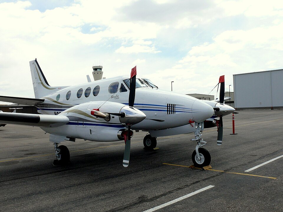 New Mexico, United States: The U.S. National Transportation Safety Board (NTSB) has revealed that a U.S. military GPS jamming exercise was underway when a Beechcraft C90 King Air air ambulance crashed into mountainous terrain near Lincoln, New Mexico, killing all four people on board. The findings were released in a preliminary report, meaning investigators have not yet determined the probable cause or contributing factors of the accident. The accident occurred at 0015 local time on May 14, 2026, after the aircraft, registered N249CP and operated by Generations Jets under Part 135 as an air ambulance flight, departed Roswell Air Center (ROW) to Sierra Blanca Regional Airport (SRR) in Ruidoso to pick up a patient for transport to Albuquerque. The flight was crewed by two pilots and carried two flight nurses employed by Trans Aero Medical Services. The crash claimed the lives of Captain Keelan Clark, First Officer Ali Kawsara, and flight nurses Sarah Clark and Jamie Novick. According to the NTSB, GPS jamming activities conducted by the U.S. military were active over the accident area during the flight. Shortly after departure, the aircraft was cleared to 12,000 feet under instrument flight rules (IFR). At 0000:26, air traffic controllers advised the crew that the aircraft had climbed to 13,000 feet, 1,000 feet above its assigned altitude. The pilot responded that the aircraft had lost GPS capability and requested headings from air traffic control. The crew initially requested the RNAV (GPS) Runway 24 approach into Sierra Blanca Regional Airport but, after losing GPS navigation, switched to the ILS Runway 24 approach. At 0001:17, the Albuquerque Air Route Traffic Control Center (ARTCC) controller contacted the operations supervisor and requested that the military stop the GPS jamming. The aircraft continued north while controllers provided radar headings. During the same period, three other aircraft also reported GPS outages, with one crew requiring additional assistance to identify a ground-based navigation aid. At about 0005, the ARTCC operations supervisor again contacted the military to stop the jamming, after which ADS-B transmissions returned to normal. At 0008, the accident crew reported having Ruidoso in sight and requested to continue visually. Controllers cleared the aircraft for a visual approach and advised the crew they could cancel IFR after descending below 9,000 feet or after landing. The pilots acknowledged the clearance and stated they would cancel IFR "in just a couple of minutes." No further radio transmissions were received. The aircraft then turned southwest toward Sierra Blanca Regional Airport. Between the airport and the aircraft lay the Capitan Mountains, which rise to 10,201 feet. Around 0010, after being informed the aircraft was on a visual approach, the military resumed the GPS jamming exercise. The King Air began descending before briefly climbing again. The final Spidertracks data point recorded the aircraft at 9,823 feet, 150 knots ground speed, and a heading of 250 degrees. Seconds later, it struck terrain at an elevation of about 9,950 feet, approximately 730 feet east and 230 feet below the Capitan Mountains Summit Radio Facility, triggering a post-impact fire that ignited a forest fire. Investigators also found that the crew's ForeFlight weather briefing included active NOTAMs warning that military GPS jamming would affect GPS, WAAS, GBAS and ADS-B navigation over a wide area encompassing the accident flight path and altitudes. Additional NOTAMs advised that Sierra Blanca Regional Airport's automated weather observation system (AWOS) was out of service, while the weather briefing indicated no METAR or TAF was available for the destination airport. The airport's published RNAV and ILS Runway 24 approach procedures also state that the procedures are not authorized when the local altimeter setting is unavailable. The NTSB emphasized that the report is preliminary and subject to change, and that it does not determine the accident's probable cause.