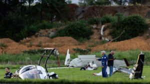 Carlisle, United States: A Cessna 150 collided with a Pennsylvania State Police Bell 407 helicopter at Carlisle Regional Airport in Cumberland County, Pennsylvania, on Wednesday evening, August 19, killing the Cessna pilot and injuring two state police troopers aboard the helicopter. The collision occurred near a runway at the airport, about 110 miles northwest of Philadelphia. The FAA identified the aircraft involved as a Cessna 150 and a Bell 407. The Cessna pilot, believed to have been the aircraft's only occupant, died in the crash. Authorities had not released the pilot's identity pending notification of next of kin. The Bell 407 was operated by the Pennsylvania State Police and was carrying two members of the department's aviation unit, Cpl. Bryce Corman and Tpr. Jason Mills. The helicopter was conducting a routine training exercise at Carlisle after operating from its Harrisburg base. According to Acting Pennsylvania State Police Commissioner Lt. Col. George Bivens, the helicopter was positioned several feet above a grassy area next to a runway when the Cessna approached from behind. The aircraft came down along the runway before veering sharply to the right at the last moment and striking the helicopter from the rear. “As that Cessna came down along that runway for an unknown reason, it veered hard to the right. At the last moment, it struck the helicopter from the rear,” Bivens said. The Cessna struck the helicopter's rear section, involving the tail rotor and then the main rotor, sending both aircraft into a violent crash. The Cessna broke into multiple pieces, while the Bell 407 lost its rotor blades and tail boom before rolling over and coming to rest on its side, partially on its roof. The two troopers were initially trapped inside the helicopter. Corman was able to push out a window and help Mills escape through the opening. Mills was believed to have suffered more serious injuries and significant bleeding, according to Bivens. Both troopers were taken to Penn State Health Milton S. Hershey Medical Center. Dr. Ashley Ludwig, the hospital's trauma medical director, said they arrived as Level 1 trauma patients but had only minor injuries and were in stable condition. One was expected to be discharged Wednesday night, while the other was admitted for further observation. Pennsylvania State Police Commissioner Col. Christopher Paris said the helicopter crew was conducting routine training when the collision occurred. He said the helicopter pilots would not have been able to see the Cessna approaching from behind. “The pilots would not have been able to even see that airplane approaching them,” Paris said. Governor Josh Shapiro visited the medical center and praised the emergency response and medical teams involved in treating the injured troopers. “Tonight could have been much worse,” Shapiro said, adding that the response was “an example of Pennsylvania at its finest.” Emergency personnel responded to the airport following the crash, and the coroner was called to the scene. Local residents Patrick Brown and Lloyd Slusser also reportedly crossed a fence and ran toward the wreckage to assist after witnessing the crash. The Cessna was reportedly from the local area, but authorities have not disclosed its departure point, destination or the purpose of its flight. The aircraft's pilot was believed to be its sole occupant. The exact cause of the collision remains undetermined. Officials said the Cessna's sudden right turn was made for an unknown reason, and investigators will examine why the aircraft veered from its approach path, the helicopter's position, airport operations and communications. Carlisle Regional Airport does not have an air traffic control tower. Pilots operating there use a common traffic radio frequency, and investigators are expected to examine those communications as part of the inquiry. State police also secured photographs and video that could assist investigators in reconstructing the collision. The FAA and National Transportation Safety Board are leading the investigation, with Pennsylvania State Police assisting. The NTSB said the wreckage would be documented and moved to a secure facility for further examination. Although the FAA and NTSB described the incident as a midair collision, Pennsylvania State Police later said the helicopter was on the ground at the time of the impact. Officials have not yet established whether the Cessna was airborne at the exact moment of contact. The distinction, along with the reason for the Cessna's sudden deviation, remains part of the investigation. No final cause has been determined, and authorities have not attributed the crash to pilot error, mechanical failure, communications issues or any other specific factor.