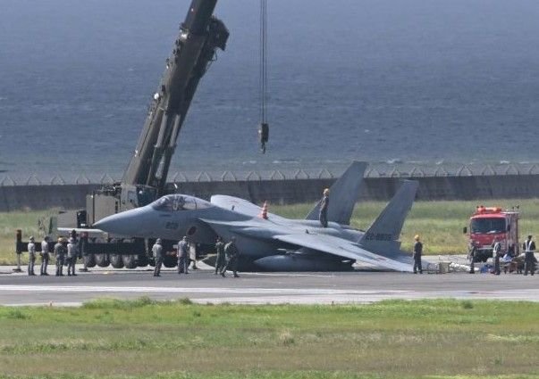 Naha, Japan: A Japan Air Self-Defense Force (JASDF) F-15J fighter jet suffered a landing-gear malfunction while landing at Naha Airport in Okinawa on August 18, forcing the closure of the airport’s second runway for about four hours and delaying dozens of civilian flights. The pilot escaped without injury. The aircraft was identified as a Mitsubishi F-15J Eagle, registration 22-8809. The single-seat fighter was operating from JASDF Naha Air Base and was returning from a scramble mission conducted as part of Japan’s response to a possible airspace intrusion. The incident occurred at around 12:55 p.m. local time as the F-15J landed on Runway 36L, also known as Naha Airport’s B Runway. According to Japan Air Self-Defense Force (JASDF) officials, the aircraft developed a problem involving its landing gear during the landing sequence. The jet subsequently became tilted and stopped on the runway. The precise mechanical cause remains under investigation. Images and video from the scene showed the aircraft resting at an angle, with its left side lowered toward the runway. The occurrence was a possible failure of the left main landing gear. Other reports said the fighter slid along the runway after the gear collapsed, with the aircraft rotating roughly 180 degrees before coming to rest facing in the opposite direction. A JASDF spokesman told Stars and Stripes that the landing gear apparently failed as the aircraft touched down shortly before 1 p.m. and that the fighter’s left wing contacted the runway before it came to a stop. The spokesman said the pilot was not injured and that the extent of damage to the aircraft was still being assessed. The aircraft was eventually removed from the runway using recovery equipment, including a crane. Naha Airport officials said the runway remained closed for approximately four hours while the fighter was removed, the area was cleaned and safety inspections were completed. Runway operations subsequently resumed. The closure had a significant effect on civilian operations because Naha Airport is a dual-use facility, serving both commercial aviation and the JASDF. With the B Runway unavailable, civilian aircraft were required to use the other runway. Airport officials said 40 commercial flights were delayed, with some delays exceeding 30 minutes. The incident also drew a response from Okinawa Governor Denny Tamaki, who described the situation as deeply regrettable and called for the cause of the incident to be investigated. The governor’s office has sought information on the circumstances surrounding the fighter’s landing and measures to prevent a recurrence. The F-15J’s condition and the precise reason for the landing-gear failure remain subject to investigation. At this stage, available official data does not establish whether the malfunction resulted from a particular component failure, maintenance issue or other technical factor.