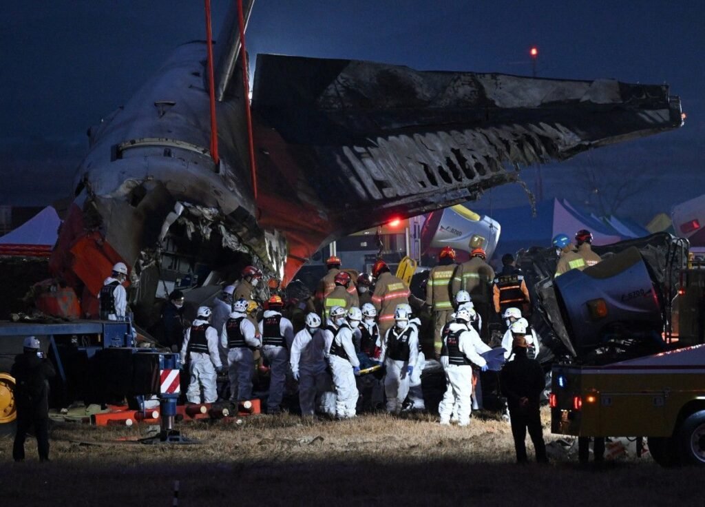 Muan, South Korea: South Korean police on August 11 raided the state-run Korea Airports Corporation (KAC), the Ministry of Land, Infrastructure and Transport and the Busan Regional Office of Aviation as investigators widened their probe into the Jeju Air crash at Muan International Airport that killed 179 people in December 2024. The searches were carried out by a special police investigation team seeking additional evidence over suspected professional negligence resulting in death or injury and possible failures by government agencies and other bodies responsible for airport safety and operations. Police said the investigation is examining both the cause of the December 29, 2024 crash and whether relevant authorities properly performed their duties. A police official said 45 people are currently facing suspicions of professional negligence resulting in death or injury, while investigators are also considering whether charges linked to causing a serious public disaster could be applied. The latest searches targeted KAC, which operates most of South Korea’s major airports except Incheon International Airport, along with the Transport Ministry and the Busan Regional Office of Aviation. The action marks another major phase in a criminal investigation that has continued for more than a year as investigators examine decisions surrounding Muan Airport’s construction, safety oversight, airport infrastructure and the response to the crash. The crash involved Jeju Air Flight 7C2216, a Boeing 737-800 operating from Bangkok to Muan. The aircraft was carrying 181 people when it attempted an emergency landing at Muan International Airport on December 29, 2024. After a bird-strike-related emergency, the aircraft landed without its landing gear deployed, slid along the runway and struck a concrete structure supporting a localizer antenna before breaking apart and catching fire. Only two crew members survived, while 179 passengers and crew members were killed. The criminal investigation has increasingly expanded beyond the aircraft itself to possible institutional and infrastructure failures. Police have been examining events dating back to the construction of Muan Airport in 1999 to determine whether decisions made during the airport’s development created conditions that contributed to the disaster. In February 2026, the special investigation team raided the Busan Regional Office of Aviation and a company involved in construction at Muan Airport, seeking evidence connected to possible contributing factors. At that stage, police had booked 45 people on suspicion of occupational negligence and were examining whether the Serious Accidents Punishment Act’s provisions concerning a serious public disaster could apply. The investigation was further expanded in March, when police raided the Transport Ministry to obtain additional material concerning the crash and the conduct of government agencies. Investigators specifically examined whether officials responsible for aviation navigation and airport operations had properly carried out their duties. Police said the probe was looking for factors dating back to the beginning of Muan Airport’s construction. A major development came in March 2026 when South Korea’s Board of Audit and Inspection identified serious shortcomings in the approval and management of airport safety infrastructure. The state auditor found that the Transport Ministry had approved 14 non-compliant localizer installations at eight airports, including Muan, and that some installations had been certified as meeting frangibility requirements despite not doing so. The audit identified 30 cases of wrongdoing or procedural failure, including shortcomings in bird-strike prevention and aviation safety management. At Muan, investigators found that a 2.4-metre-high concrete embankment supporting the localizer had been built partly to reduce construction costs because the terrain around the runway and Runway End Safety Area was sloped. The Board of Audit and Inspection said the structure had been approved by the Transport Ministry in 2003 without an adequate vulnerability assessment. Korea Airports Corporation later requested a review of the structure in 2007, but no changes were made. The structure was subsequently reinforced during a modernization project between 2019 and 2024. International aviation standards call for localizer installations in areas exposed to aircraft impact to be designed so that they can break apart rather than present a rigid obstacle. The state audit found that the ministry had continued to certify such installations and approve inspections that incorrectly indicated compliance for periods extending as long as 22 years. The Transport Ministry said it “humbly accepted” the audit findings and said it would take strict follow-up measures, including improvements to localizer structures and stronger bird-strike prevention. Korea Airports Corporation also said it was implementing improvements recommended in the audit. The infrastructure findings have become particularly significant because a separate government-commissioned simulation examined what might have happened had the concrete embankment not been present at the end of the runway. The simulation, cited in January 2026 reporting, suggested the outcome could have been substantially different without the rigid structure. The findings intensified scrutiny of how the localizer installation was designed and approved. The criminal probe is also unfolding alongside a renewed examination of the accident investigation itself. In May 2026, President Lee Jae Myung visited Muan International Airport after additional human remains were discovered during renewed recovery operations more than a year after the crash. He called for a thorough reinvestigation and criticised shortcomings in the original recovery process. “Given the size and condition (of the additional remains), they should not have been overlooked,” Lee said, adding that “the lax handling of the scene was clearly a problem.” He also instructed officials to consider using outside experts for the reinvestigation. The renewed investigation followed concerns that the original recovery operation had not fully recovered victims’ remains and that officials lacked adequate procedures and oversight. The discovery of additional remains prompted the government to revisit not only the recovery process but also the wider handling of the disaster. The technical investigation into the crash had earlier established evidence of a bird strike. A preliminary accident report released in January 2025 found feathers and blood stains in both engines of the Boeing 737-800. DNA testing identified the remains as Baikal teals, migratory ducks that winter in South Korea. The report, however, did not establish that the bird strike alone caused the crash. It also noted that the flight data recorder and cockpit voice recorder stopped recording about four minutes before impact, leaving critical portions of the final sequence unavailable. The preliminary investigation said authorities would conduct further examinations of the engines, recorders, air traffic control data, bird-strike evidence and the localizer structure. Subsequent reporting in July 2025 cited a source familiar with the investigation as saying there was “clear evidence” that the pilots shut down the less-damaged engine after the bird strike. However, that finding was part of the continuing technical investigation and was disputed by victims’ families, who questioned aspects of the investigation and its transparency. The crash therefore remains under examination on several fronts: the bird strike and resulting aircraft systems problems, the sequence of cockpit decisions, the loss of recorder data, the runway and airport infrastructure, the approval and maintenance of the localizer structure, bird-strike prevention, regulatory oversight and the actions of government agencies before and after the accident. The August 11 raids represent the latest step in the separate criminal investigation into potential responsibility and negligence. Police are now seeking additional records from the organisations responsible for airport operation, aviation oversight and infrastructure, while considering whether the conduct of officials and other responsible parties could amount to professional negligence or a serious public disaster offence. The full accident investigation has yet to provide a final public account resolving all outstanding questions surrounding the crash. The latest police action, coming after the state audit findings and the government's renewed examination of the crash site, places greater focus on whether failures in airport design, regulatory approval, safety oversight or emergency response contributed to the scale of the tragedy.