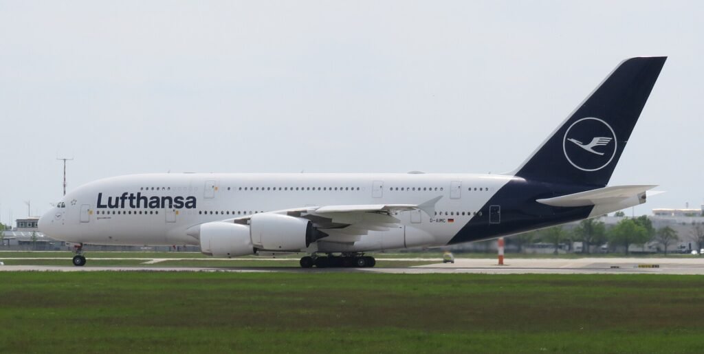 Munich, Germany: A Lufthansa Airbus A380-800 operating flight LH459 from San Francisco International Airport to Munich Airport touched down prematurely near the eastern threshold of Munich’s southern runway on Monday evening, August 17, 2026, damaging runway-threshold lighting. The aircraft, registered D-AIML, was carrying 351 passengers after completing the approximately 11-hour transatlantic flight from San Francisco, United States, to Munich, Germany. All passengers and crew were able to leave the aircraft normally, with no injuries reported. Flight records identify D-AIML as an Airbus A380-841 operated by Lufthansa, while Lufthansa’s published schedule confirms LH459 operates between San Francisco and Munich. According to Lufthansa, the aircraft touched down on the concrete surface before the white-marked runway threshold. During the premature touchdown, the aircraft struck lighting installed around the runway threshold, causing damage to the runway’s visual guidance system. Lufthansa spokesperson Jörg Waber said in a statement, “We can confirm that an AirVIbus A380-800 damaged runway lighting in the area of the runway threshold.” He added that the aircraft had arrived from San Francisco with 351 passengers, subsequently taxied to its assigned position and that all passengers left the aircraft normally. The incident occurred on Munich Airport’s southern runway, identified as Runway 26L when used for approaches from the east. The Deutsche Flugsicherung describes Runway 26L as Munich’s southern runway and says aircraft approaching it from the east use its instrument landing system. Munich Airport characterized the infrastructure damage as minor. According to the airport, a “minor damage” to lighting was identified around the eastern threshold of the southern runway. The damaged lighting was repaired promptly, allowing the runway to return to service less than an hour after the A380 landed. The exact circumstances that caused the A380 to touch down before the designated threshold remain unclear. No official finding has attributed the event to pilot error, weather, aircraft malfunction, runway conditions or any problem with the airport’s approach system. The aircraft touched down short of the marked threshold and that its landing gear struck approach lights. The cause remains under investigation. Germany’s Federal Bureau of Aircraft Accident Investigation, or BFU, has opened an investigation into the occurrence. The A380 involved was approximately 13 years old and carried the registration D-AIML. Flight-history records identify the aircraft as an Airbus A380-841 operated by Lufthansa. The airline’s A380 configuration can accommodate up to 509 passengers, although 351 passengers were onboard LH459 during this particular flight. Separately, on August 15, 2026, a Vietnam Airlines Boeing 787-9 bound for Hanoi experienced an unusually long takeoff run at Munich Airport. The aircraft continued accelerating almost to the end of Runway 26L and reportedly travelled about 120 metres beyond the paved surface before becoming airborne. During the extremely late rotation, its rear underside struck the ground, causing a tailstrike and damage to the aft fuselage. After takeoff, warnings for tail contact and low tyre pressure prompted the crew to remain near Munich at around 9,000 feet for about two hours before returning. The aircraft sustained further landing-gear and tyre damage, with several tyres damaged or deflated, and was unable to taxi after landing. It was carrying 271 passengers and 16 crew, all of whom were reported safe. German authorities are leading the investigation, with Vietnamese investigators assisting, while the cause of the unusually prolonged takeoff remains under investigation.