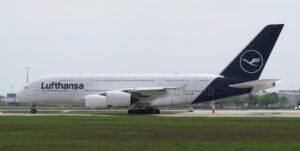 Munich, Germany: A Lufthansa Airbus A380-800 operating flight LH459 from San Francisco International Airport to Munich Airport touched down prematurely near the eastern threshold of Munich’s southern runway on Monday evening, August 17, 2026, damaging runway-threshold lighting. The aircraft, registered D-AIML, was carrying 351 passengers after completing the approximately 11-hour transatlantic flight from San Francisco, United States, to Munich, Germany. All passengers and crew were able to leave the aircraft normally, with no injuries reported. Flight records identify D-AIML as an Airbus A380-841 operated by Lufthansa, while Lufthansa’s published schedule confirms LH459 operates between San Francisco and Munich. According to Lufthansa, the aircraft touched down on the concrete surface before the white-marked runway threshold. During the premature touchdown, the aircraft struck lighting installed around the runway threshold, causing damage to the runway’s visual guidance system. Lufthansa spokesperson Jörg Waber said in a statement, “We can confirm that an AirVIbus A380-800 damaged runway lighting in the area of the runway threshold.” He added that the aircraft had arrived from San Francisco with 351 passengers, subsequently taxied to its assigned position and that all passengers left the aircraft normally. The incident occurred on Munich Airport’s southern runway, identified as Runway 26L when used for approaches from the east. The Deutsche Flugsicherung describes Runway 26L as Munich’s southern runway and says aircraft approaching it from the east use its instrument landing system. Munich Airport characterized the infrastructure damage as minor. According to the airport, a “minor damage” to lighting was identified around the eastern threshold of the southern runway. The damaged lighting was repaired promptly, allowing the runway to return to service less than an hour after the A380 landed. The exact circumstances that caused the A380 to touch down before the designated threshold remain unclear. No official finding has attributed the event to pilot error, weather, aircraft malfunction, runway conditions or any problem with the airport’s approach system. The aircraft touched down short of the marked threshold and that its landing gear struck approach lights. The cause remains under investigation. Germany’s Federal Bureau of Aircraft Accident Investigation, or BFU, has opened an investigation into the occurrence. The A380 involved was approximately 13 years old and carried the registration D-AIML. Flight-history records identify the aircraft as an Airbus A380-841 operated by Lufthansa. The airline’s A380 configuration can accommodate up to 509 passengers, although 351 passengers were onboard LH459 during this particular flight. Separately, on August 15, 2026, a Vietnam Airlines Boeing 787-9 bound for Hanoi experienced an unusually long takeoff run at Munich Airport. The aircraft continued accelerating almost to the end of Runway 26L and reportedly travelled about 120 metres beyond the paved surface before becoming airborne. During the extremely late rotation, its rear underside struck the ground, causing a tailstrike and damage to the aft fuselage. After takeoff, warnings for tail contact and low tyre pressure prompted the crew to remain near Munich at around 9,000 feet for about two hours before returning. The aircraft sustained further landing-gear and tyre damage, with several tyres damaged or deflated, and was unable to taxi after landing. It was carrying 271 passengers and 16 crew, all of whom were reported safe. German authorities are leading the investigation, with Vietnamese investigators assisting, while the cause of the unusually prolonged takeoff remains under investigation.