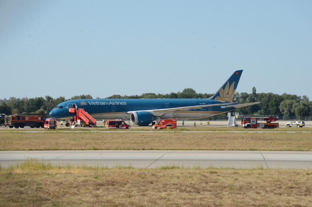 Vietnam Airlines Boeing 787 Suffers Tailstrike After Extended Takeoff Run At Munich SEO DES: The crew climbed to 9,000 feet and remained near Munich for two hours; Returned after tail-contact and low-tyre-pressure warnings, with damage SOCIAL: A Vietnam Airlines Boeing 787-9 flying from Munich to Hanoi took an unusually long takeoff roll on Runway 26L on August 15, 2026, before becoming airborne near the runway end. The aircraft reportedly travelled about 120 metres beyond the paved surface, with a tailstrike occurring during the late rotation. After takeoff, the crew climbed to around 9,000 feet and remained near Munich for about two hours before returning to the airport after warnings for tail contact and low tyre pressure. The aircraft sustained tail, landing-gear and tyre damage and could not taxi away after landing. The aircraft carried 271 passengers and 16 crew, all of whom were reported safe with no injuries. German authorities are leading the investigation, with Vietnamese investigators assisting, while the exact cause of the prolonged takeoff remains under investigation. Munich, Germany: A Vietnam Airlines Boeing 787-9 bound for Hanoi took an unusually long takeoff run from Munich Airport on August 15 before finally becoming airborne beyond the normal paved runway area, in an incident that resulted in runway damage, a tail strike and subsequent damage to the aircraft's landing gear. The aircraft later returned to Munich after remaining airborne for about two hours, with no injuries reported among the passengers or crew. The exact reason for the aircraft's prolonged acceleration and extremely late liftoff remains under investigation. The most significant part of the incident occurred during the takeoff roll. Video footage recorded from inside the cabin and from outside the airport shows the 787 accelerating along Runway 26L for an unusually long distance before rotation. Instead of lifting off with substantial runway remaining, the aircraft continued almost to the end of the approximately 4,000-metre runway. Reports based on flight-tracking data indicate that the aircraft reached the runway end area before becoming airborne, with reports putting the excursion beyond the paved surface at roughly 120 metres. The available video is particularly significant because it shows that the issue was not simply a conventional tailstrike during an otherwise normal rotation. The aircraft appears to remain on the ground for an unusually long period, with the runway threshold passing while the aircraft was still accelerating. It eventually rotated at the very end of the runway area, after which a large cloud of dust was visible beneath the rear of the aircraft. The reason for the unusually slow or prolonged takeoff has not been established. Online speculation has included possibilities such as an incorrect takeoff configuration, incorrect thrust or a problem affecting the aircraft's acceleration. However, none of those explanations has been confirmed by Vietnam Airlines or investigators and should not be presented as the cause. Vietnam Airlines has described the event as resulting from a technical issue and said the crew followed safety procedures. The airline has not publicly identified a specific technical failure responsible for the aircraft's unusually long takeoff roll. That distinction is important because the aircraft's subsequent warnings and damage do not, by themselves, establish what caused the initial lack of acceleration. Vietnam's aviation authorities have provided additional information on what happened after the aircraft became airborne. According to the latest reporting on the Civil Aviation Authority of Vietnam's information, warnings indicating tail contact and low tyre pressure were triggered shortly after takeoff. The authorities said the aircraft subsequently returned to Munich, while German authorities led the investigation with Vietnamese investigators assisting. After the aircraft finally lifted off, the crew did not immediately attempt to land. The Boeing 787 climbed to around 9,000 feet and remained in the Munich area for approximately two hours. During that period, the crew assessed the situation and reduced the aircraft's weight before returning to the airport. The tailstrike occurred as the aircraft became airborne after the exceptionally long takeoff run. The rear underside of the aircraft contacted the ground, producing the visible dust plume captured on video. A tailstrike can damage the aircraft's lower aft fuselage, pressure vessel, structural frames, systems, wiring and other components around the tail area. In this case, photographs and video circulating after the incident showed damage around the rear fuselage and the loss or damage of the Boeing 787's tailstrike protection component. The full extent of the structural damage, however, remains subject to technical inspection. The aircraft also sustained landing-gear and tyre damage. Reports indicate that several tyres were damaged or deflated, and footage following the return showed the aircraft unable to taxi away from the runway under its own power. The landing-gear damage also resulted in debris being left on the runway. The aircraft eventually landed back at Munich Airport, using the airport's other runway. Following the landing, the affected aircraft remained on the runway, forcing the closure of the runway and requiring airport authorities to clear debris and deal with the disabled aircraft. Traffic was subsequently handled through the other available runway, causing disruption at the German hub. There were no reported injuries among the passengers or crew. The aircraft was carrying passengers and crew on the Munich-Hanoi service; Vietnam Airlines has reported the total as 271 passengers and 16 crew members. All occupants were reported safe after the aircraft returned to Munich. The incident is now being examined by the relevant German authorities, with Vietnamese aviation investigators assisting. Investigators will need to establish why the Boeing 787 did not achieve the expected acceleration during the takeoff roll, why the aircraft reached the end of the runway area before becoming airborne and whether any technical, operational or performance-related factor contributed to the event.