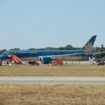 Vietnam Airlines Boeing 787 Suffers Tailstrike After Extended Takeoff Run At Munich SEO DES: The crew climbed to 9,000 feet and remained near Munich for two hours; Returned after tail-contact and low-tyre-pressure warnings, with damage SOCIAL: A Vietnam Airlines Boeing 787-9 flying from Munich to Hanoi took an unusually long takeoff roll on Runway 26L on August 15, 2026, before becoming airborne near the runway end. The aircraft reportedly travelled about 120 metres beyond the paved surface, with a tailstrike occurring during the late rotation. After takeoff, the crew climbed to around 9,000 feet and remained near Munich for about two hours before returning to the airport after warnings for tail contact and low tyre pressure. The aircraft sustained tail, landing-gear and tyre damage and could not taxi away after landing. The aircraft carried 271 passengers and 16 crew, all of whom were reported safe with no injuries. German authorities are leading the investigation, with Vietnamese investigators assisting, while the exact cause of the prolonged takeoff remains under investigation. Munich, Germany: A Vietnam Airlines Boeing 787-9 bound for Hanoi took an unusually long takeoff run from Munich Airport on August 15 before finally becoming airborne beyond the normal paved runway area, in an incident that resulted in runway damage, a tail strike and subsequent damage to the aircraft's landing gear. The aircraft later returned to Munich after remaining airborne for about two hours, with no injuries reported among the passengers or crew. The exact reason for the aircraft's prolonged acceleration and extremely late liftoff remains under investigation. The most significant part of the incident occurred during the takeoff roll. Video footage recorded from inside the cabin and from outside the airport shows the 787 accelerating along Runway 26L for an unusually long distance before rotation. Instead of lifting off with substantial runway remaining, the aircraft continued almost to the end of the approximately 4,000-metre runway. Reports based on flight-tracking data indicate that the aircraft reached the runway end area before becoming airborne, with reports putting the excursion beyond the paved surface at roughly 120 metres. The available video is particularly significant because it shows that the issue was not simply a conventional tailstrike during an otherwise normal rotation. The aircraft appears to remain on the ground for an unusually long period, with the runway threshold passing while the aircraft was still accelerating. It eventually rotated at the very end of the runway area, after which a large cloud of dust was visible beneath the rear of the aircraft. The reason for the unusually slow or prolonged takeoff has not been established. Online speculation has included possibilities such as an incorrect takeoff configuration, incorrect thrust or a problem affecting the aircraft's acceleration. However, none of those explanations has been confirmed by Vietnam Airlines or investigators and should not be presented as the cause. Vietnam Airlines has described the event as resulting from a technical issue and said the crew followed safety procedures. The airline has not publicly identified a specific technical failure responsible for the aircraft's unusually long takeoff roll. That distinction is important because the aircraft's subsequent warnings and damage do not, by themselves, establish what caused the initial lack of acceleration. Vietnam's aviation authorities have provided additional information on what happened after the aircraft became airborne. According to the latest reporting on the Civil Aviation Authority of Vietnam's information, warnings indicating tail contact and low tyre pressure were triggered shortly after takeoff. The authorities said the aircraft subsequently returned to Munich, while German authorities led the investigation with Vietnamese investigators assisting. After the aircraft finally lifted off, the crew did not immediately attempt to land. The Boeing 787 climbed to around 9,000 feet and remained in the Munich area for approximately two hours. During that period, the crew assessed the situation and reduced the aircraft's weight before returning to the airport. The tailstrike occurred as the aircraft became airborne after the exceptionally long takeoff run. The rear underside of the aircraft contacted the ground, producing the visible dust plume captured on video. A tailstrike can damage the aircraft's lower aft fuselage, pressure vessel, structural frames, systems, wiring and other components around the tail area. In this case, photographs and video circulating after the incident showed damage around the rear fuselage and the loss or damage of the Boeing 787's tailstrike protection component. The full extent of the structural damage, however, remains subject to technical inspection. The aircraft also sustained landing-gear and tyre damage. Reports indicate that several tyres were damaged or deflated, and footage following the return showed the aircraft unable to taxi away from the runway under its own power. The landing-gear damage also resulted in debris being left on the runway. The aircraft eventually landed back at Munich Airport, using the airport's other runway. Following the landing, the affected aircraft remained on the runway, forcing the closure of the runway and requiring airport authorities to clear debris and deal with the disabled aircraft. Traffic was subsequently handled through the other available runway, causing disruption at the German hub. There were no reported injuries among the passengers or crew. The aircraft was carrying passengers and crew on the Munich-Hanoi service; Vietnam Airlines has reported the total as 271 passengers and 16 crew members. All occupants were reported safe after the aircraft returned to Munich. The incident is now being examined by the relevant German authorities, with Vietnamese aviation investigators assisting. Investigators will need to establish why the Boeing 787 did not achieve the expected acceleration during the takeoff roll, why the aircraft reached the end of the runway area before becoming airborne and whether any technical, operational or performance-related factor contributed to the event.